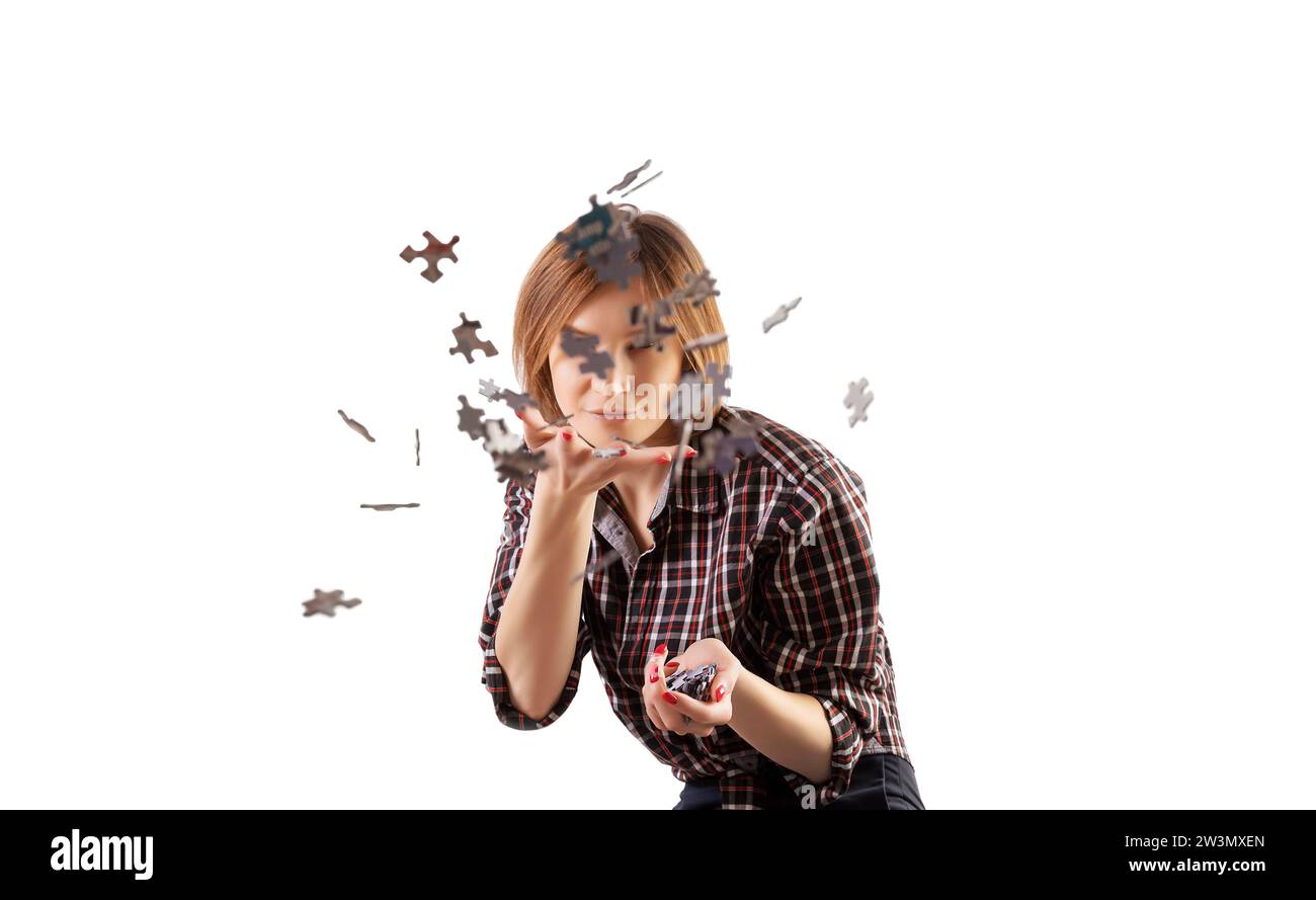 Simpatica ragazza spruzza intorno ai puzzle. Il concetto di scuola prescolare e di scuola a casa. Divertenti giochi da tavolo. Supporti misti Foto Stock