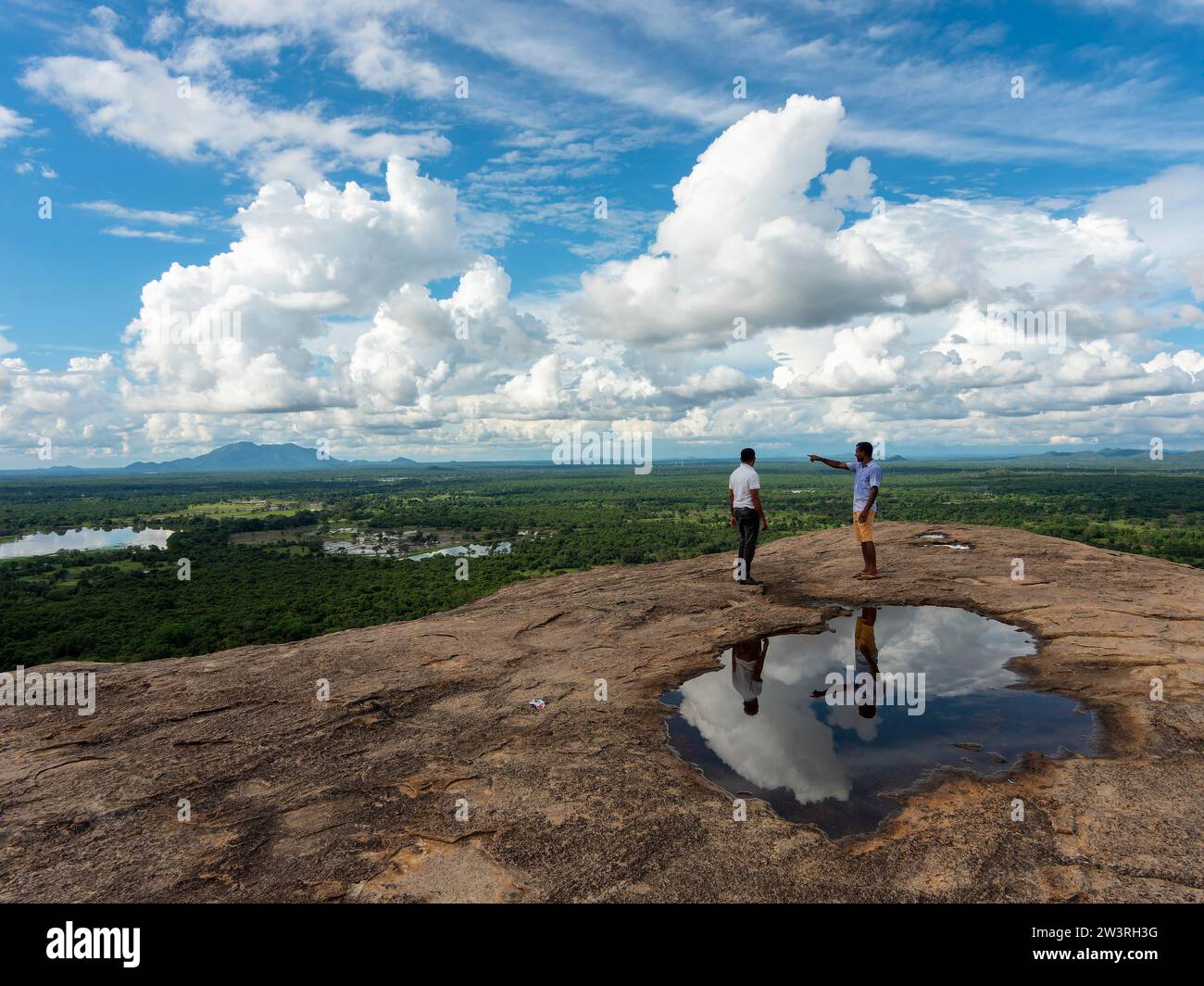 Uomini in piedi sulle rocce, riflessi in una pozzanghera, vista del paesaggio, Pidurangala, Sri Lanka Foto Stock