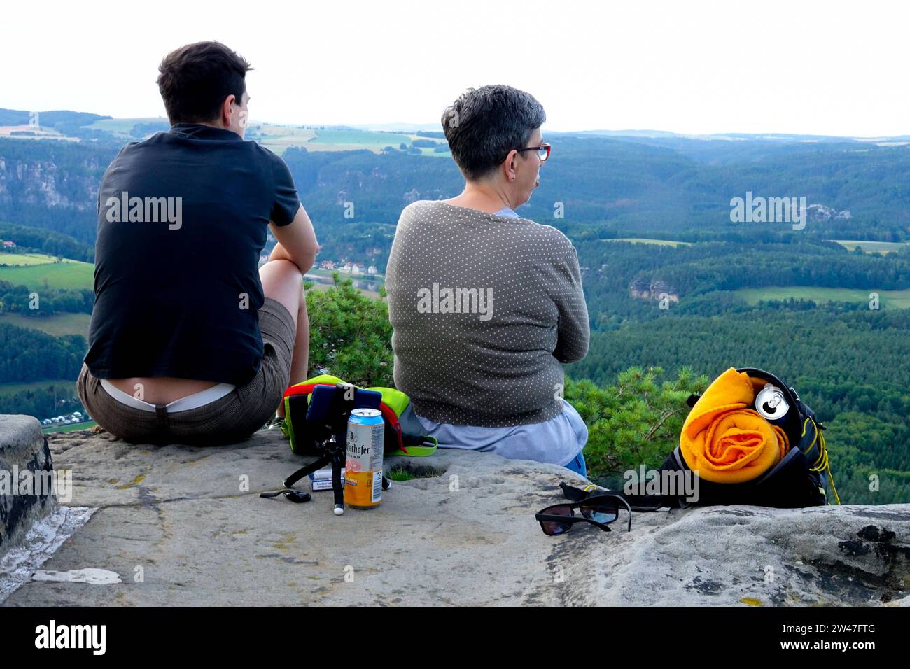 Una coppia che riposa su una delle vette e guarda il paesaggio, Elba Montagne di arenaria Sassonia Svizzera Germania Foto Stock