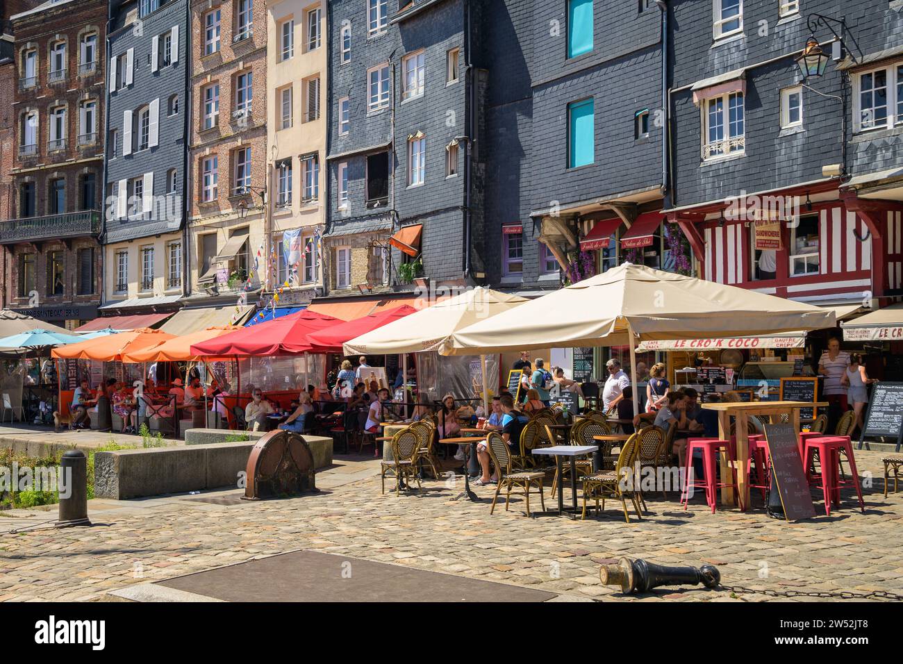 Honfleur, Francia - 24 luglio 2022: Case e ristoranti nel vecchio porto di Honfleur in una giornata di sole in estate, cielo blu Foto Stock