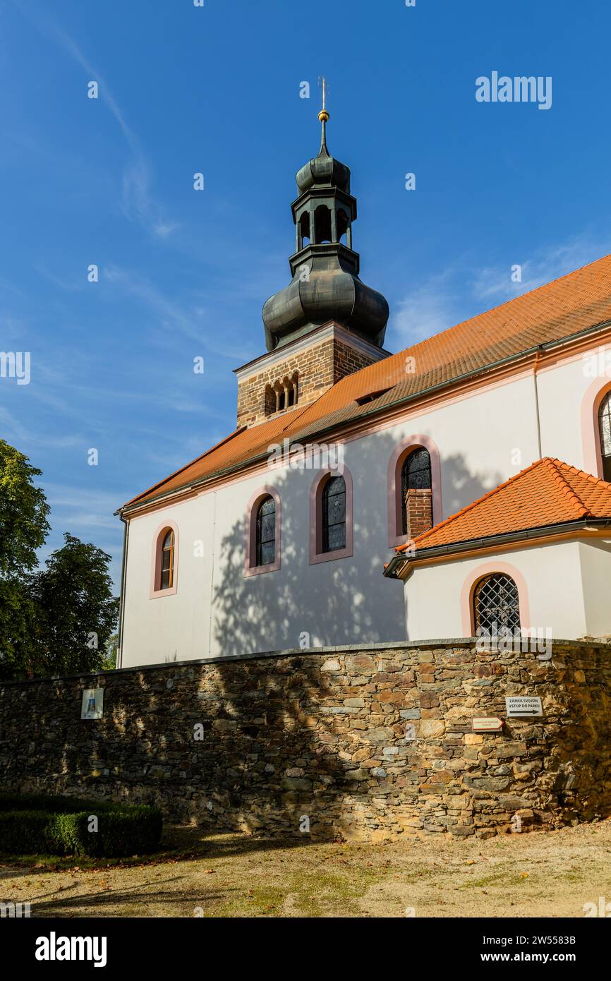 Svojsin, Repubblica Ceca - 13 ottobre 2023: Vista della chiesa di San Pietro e Pavel con una torre romanica in pietra. Erba gialla secca e parete di pietra Foto Stock