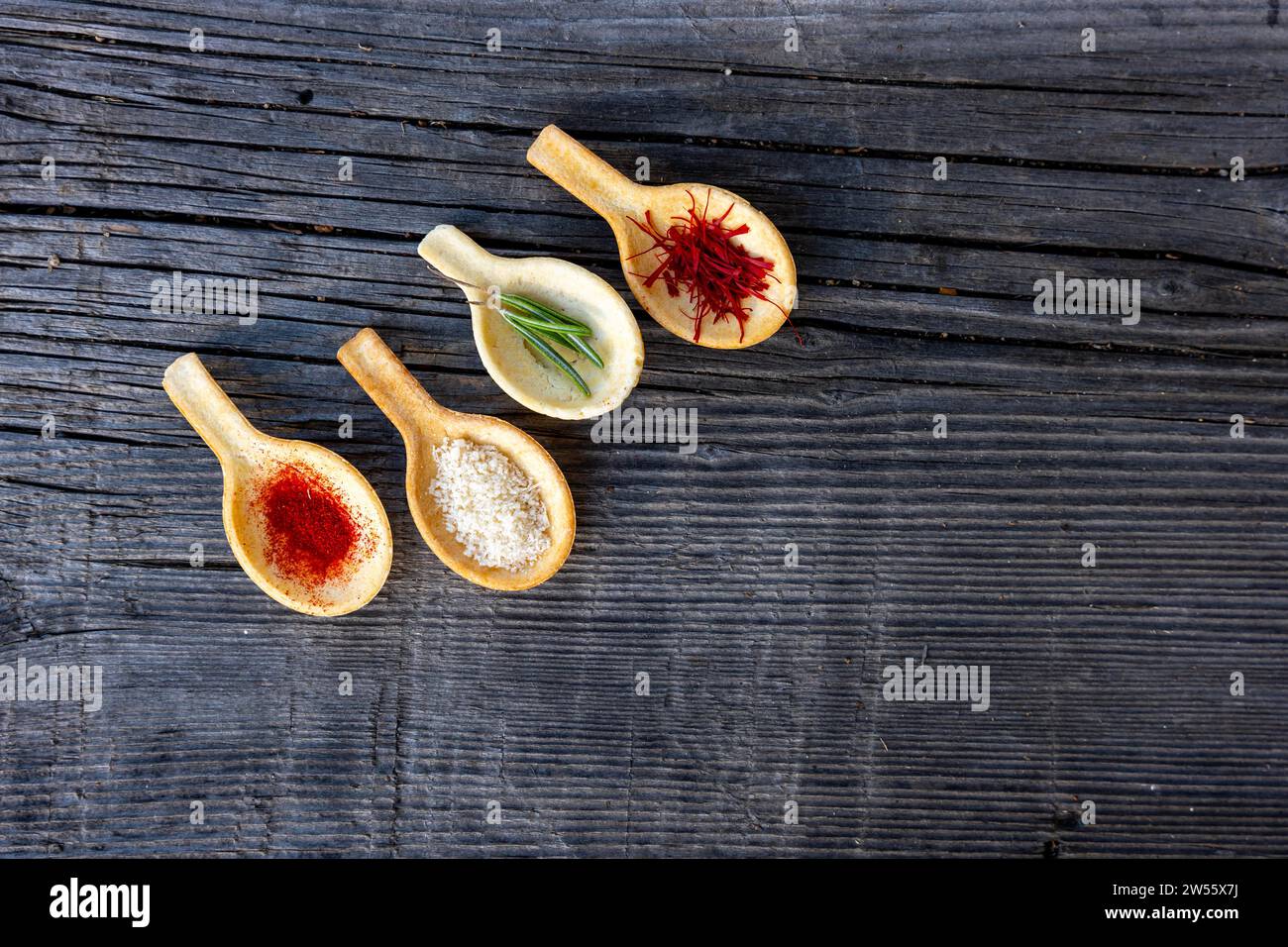 Specie a cucchiaio come zafferano e parmigiano e rosmarino su un tavolo di legno con luce solare in Svizzera Foto Stock