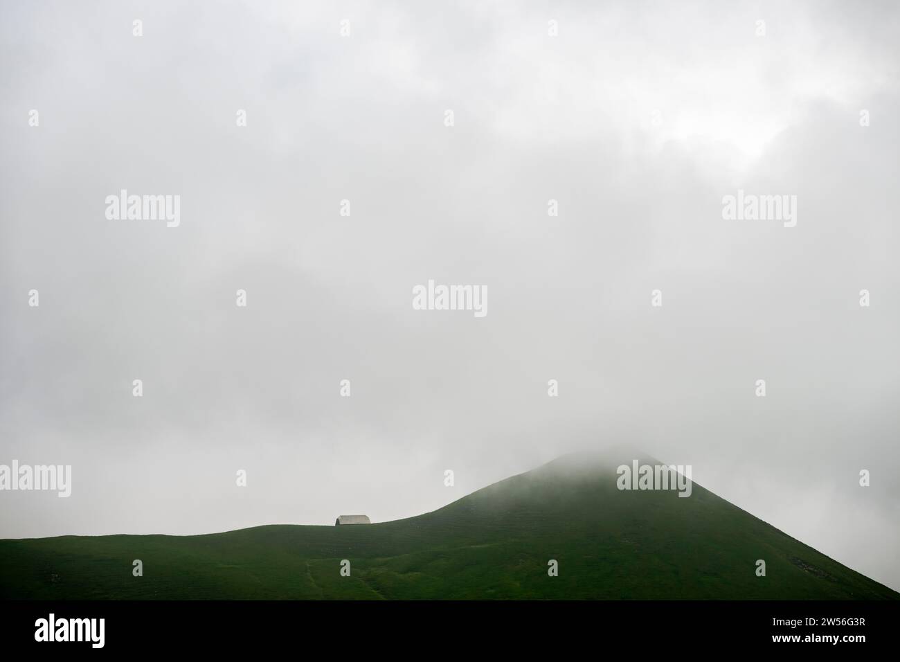 Cima erbosa con rifugio nella nebbia, Interlaken, Oberland Bernese, Svizzera Foto Stock