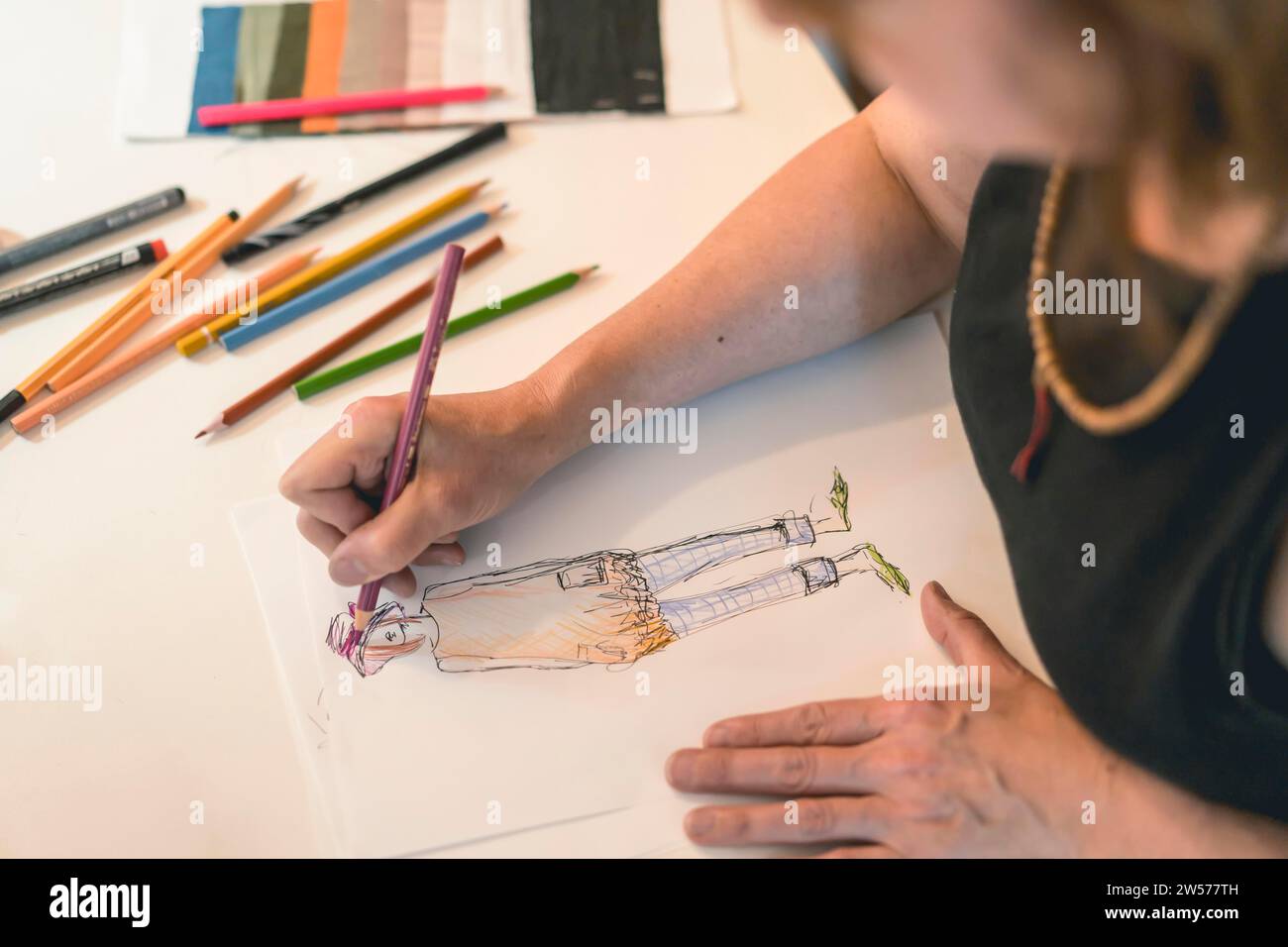 Stilista che disegna un disegno di moda con matite colorate Foto Stock