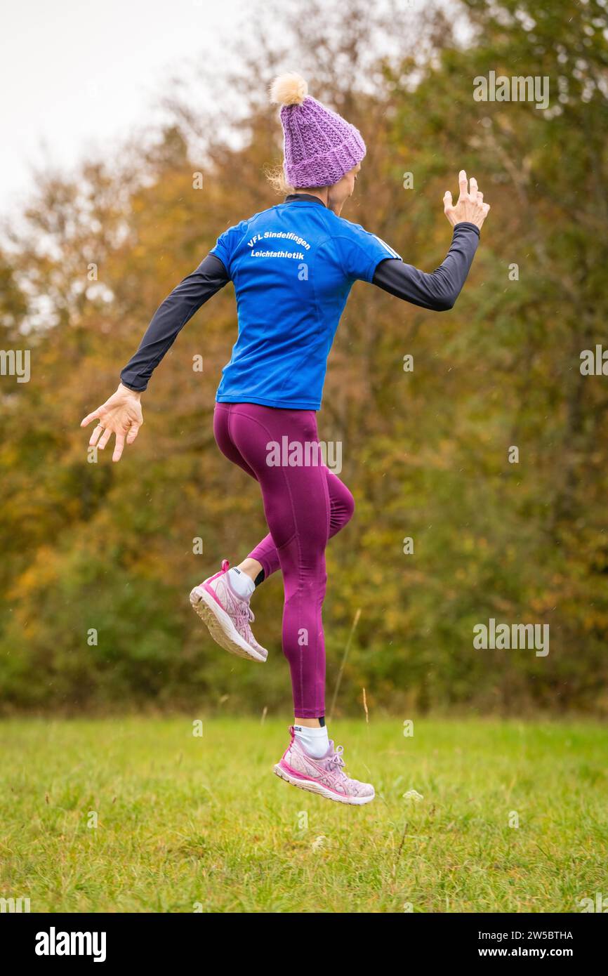 Una vista posteriore dinamica di una donna che fa jogging nella foresta autunnale, Gechingen, Foresta Nera, Germania Foto Stock