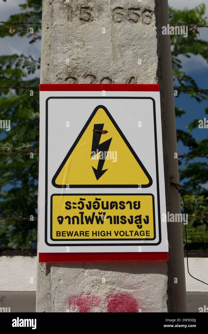 fate attenzione al segnale di alta tensione, scritto in tailandese e inglese, con simbolo di avvertimento, in phetchabun, thailandia Foto Stock