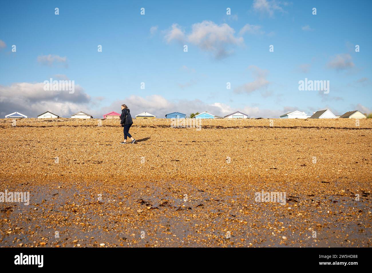 Rifugi sulla spiaggia di Hayling Island a immagine paesaggistica in inverno con escursionisti Foto Stock