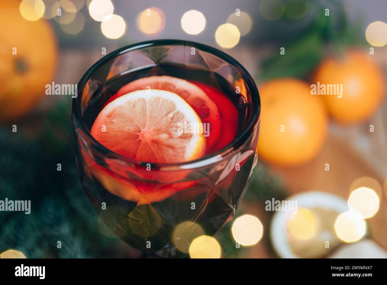 Bicchiere di vino con VIN brulé con frutta e decorazioni natalizie. Sfondo bokeh sfocato. Primo piano. Foto Stock