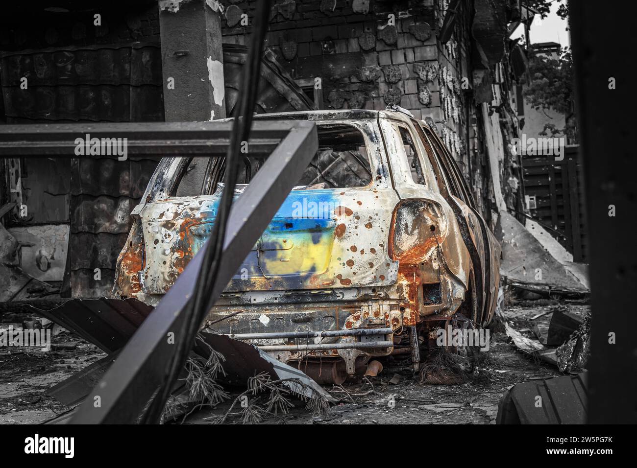 Auto bruciata con bandiera Ucraina dipinta sul bagagliaio parcheggiata nel cortile di una casa distrutta a causa del bombardamento di Malta. Irpin, regione di Kiev, 2022. Guerra in U Foto Stock