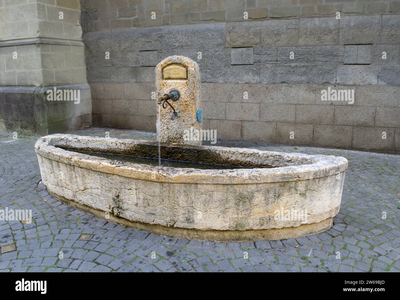 I passanti devoti bevono dall'umile fontana di St. Francis Church a Losanna, Svizzera Foto Stock