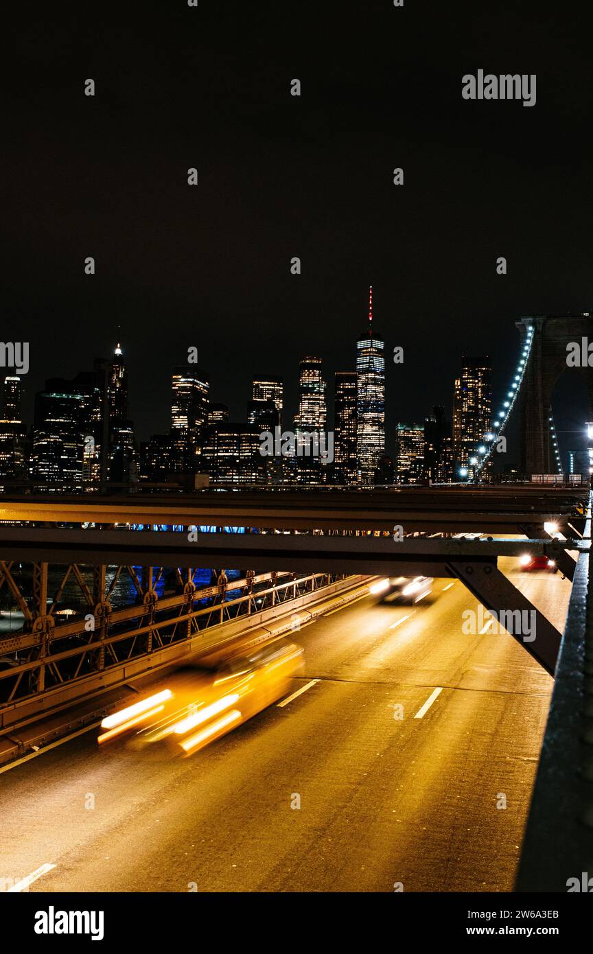 Vivace vista notturna di Manhattan da un ponte con traffico in rapido movimento. Foto Stock