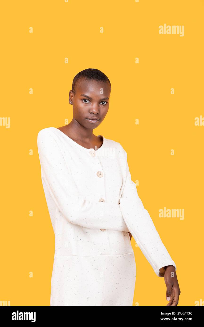 Ritratto di una giovane donna afro-americana sicura e calma con i capelli corti in bianco mentre guardi la macchina fotografica su sfondo giallo Foto Stock
