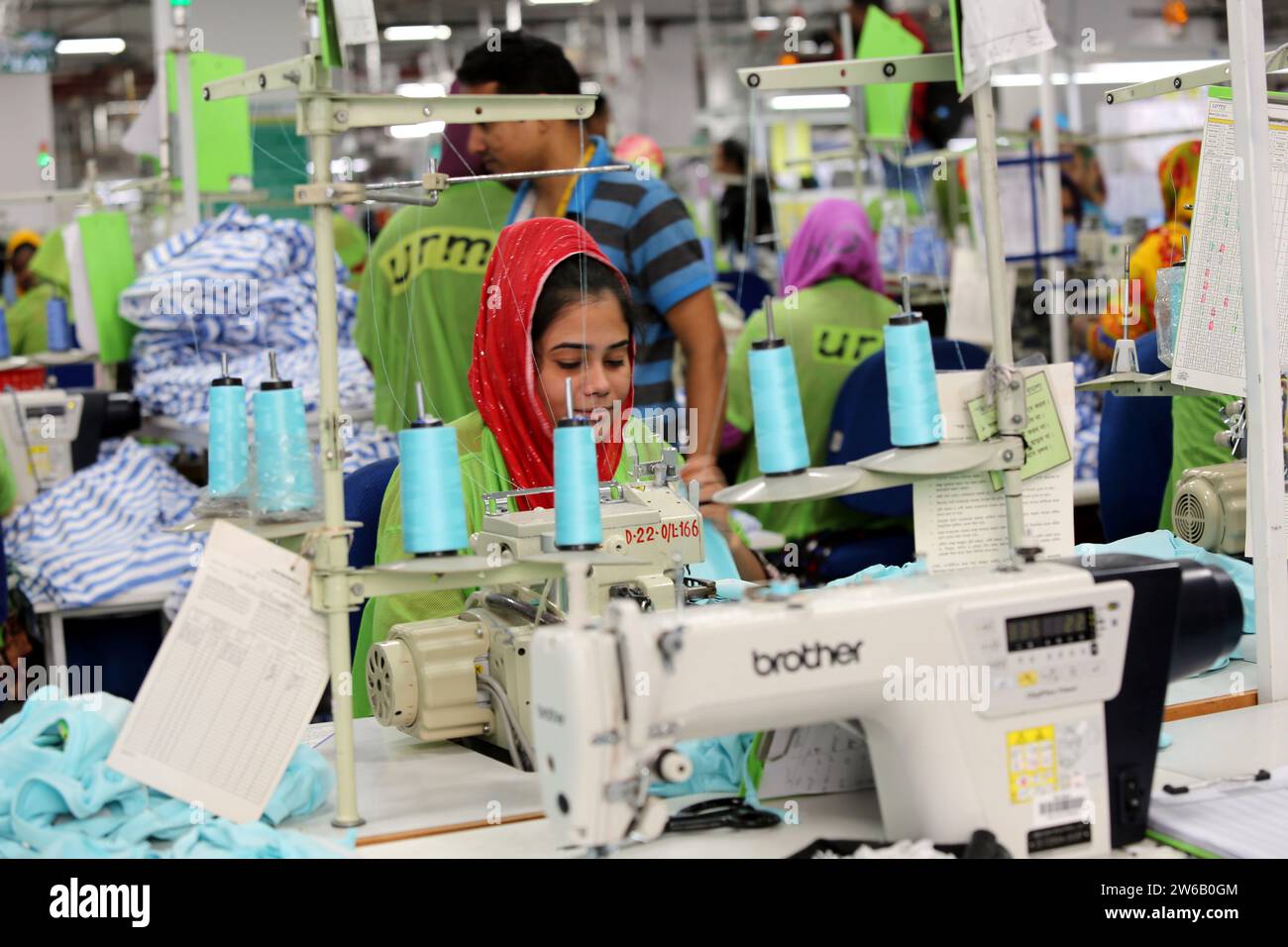 Un lavoratore di indumenti pronto all'uso lavora in una fabbrica di indumenti a Dacca, Bangladesh, il 21 dicembre 2023. Le fabbriche tessili del Bangladesh producono cl Foto Stock