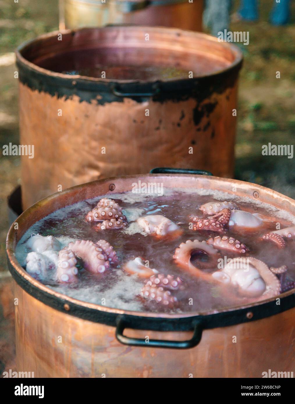 Il metodo tradizionale di cottura galiziano è raffigurato con tentacoli di polpo che bollono in un grande recipiente di rame riempito d'acqua, che simula su una fiamma aperta, sl Foto Stock