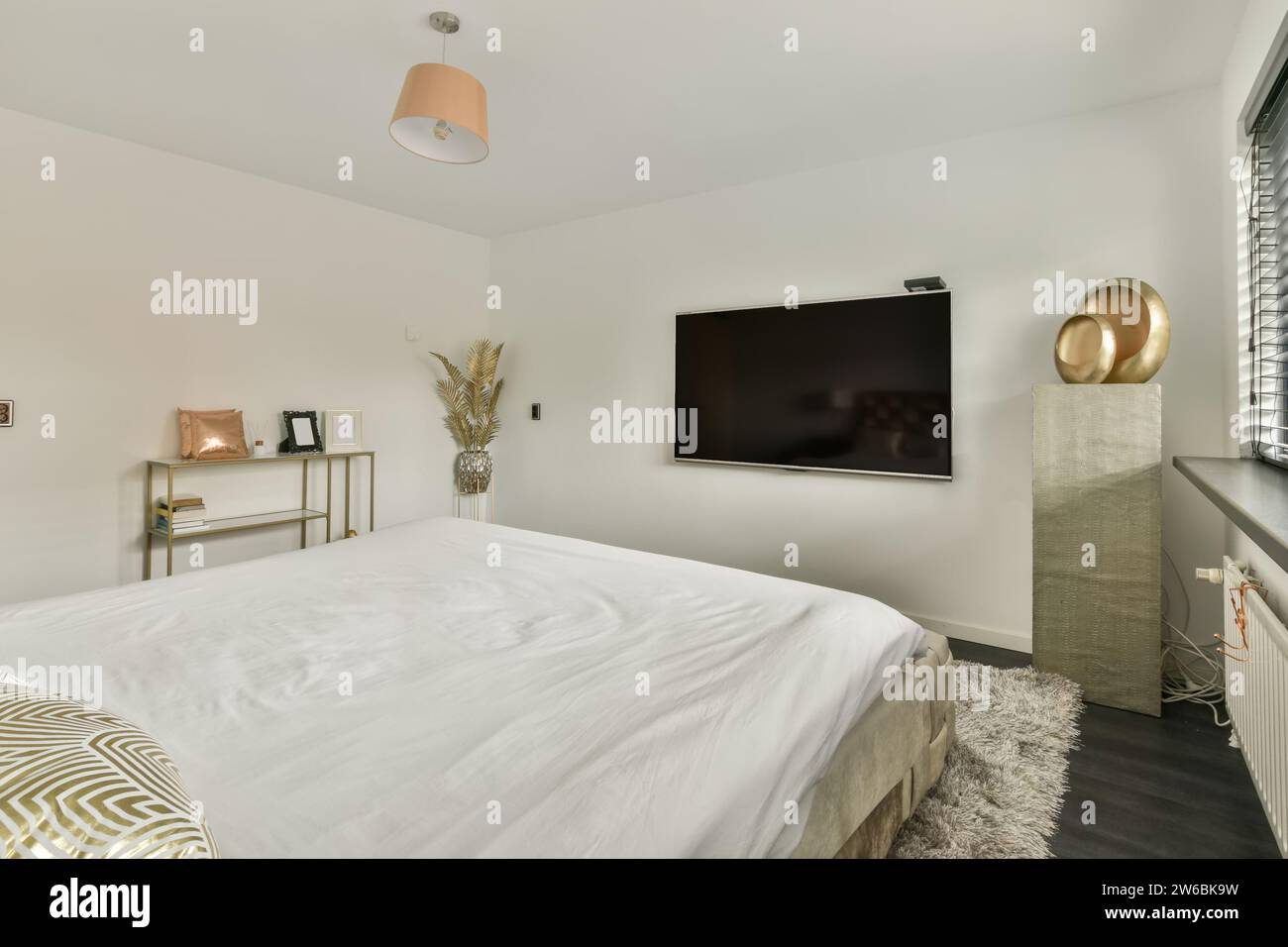 Camera moderna con letto grande, TV a schermo piatto e arredi eleganti dal design minimalista. Foto Stock