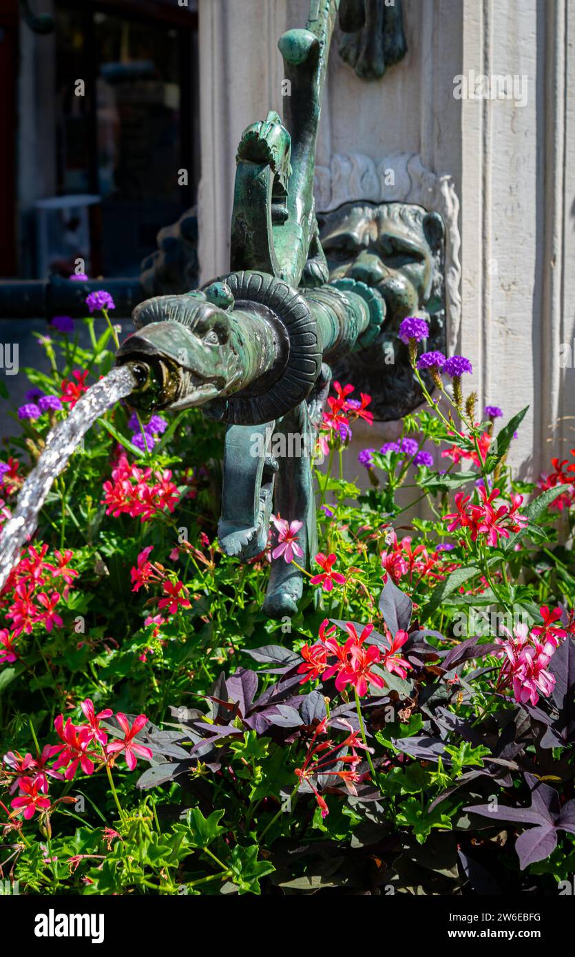 I fiori circondano una fontana ornata di animali presso la fontana della Signora della giustizia a Place de la Palud Losanna, Svizzera Foto Stock