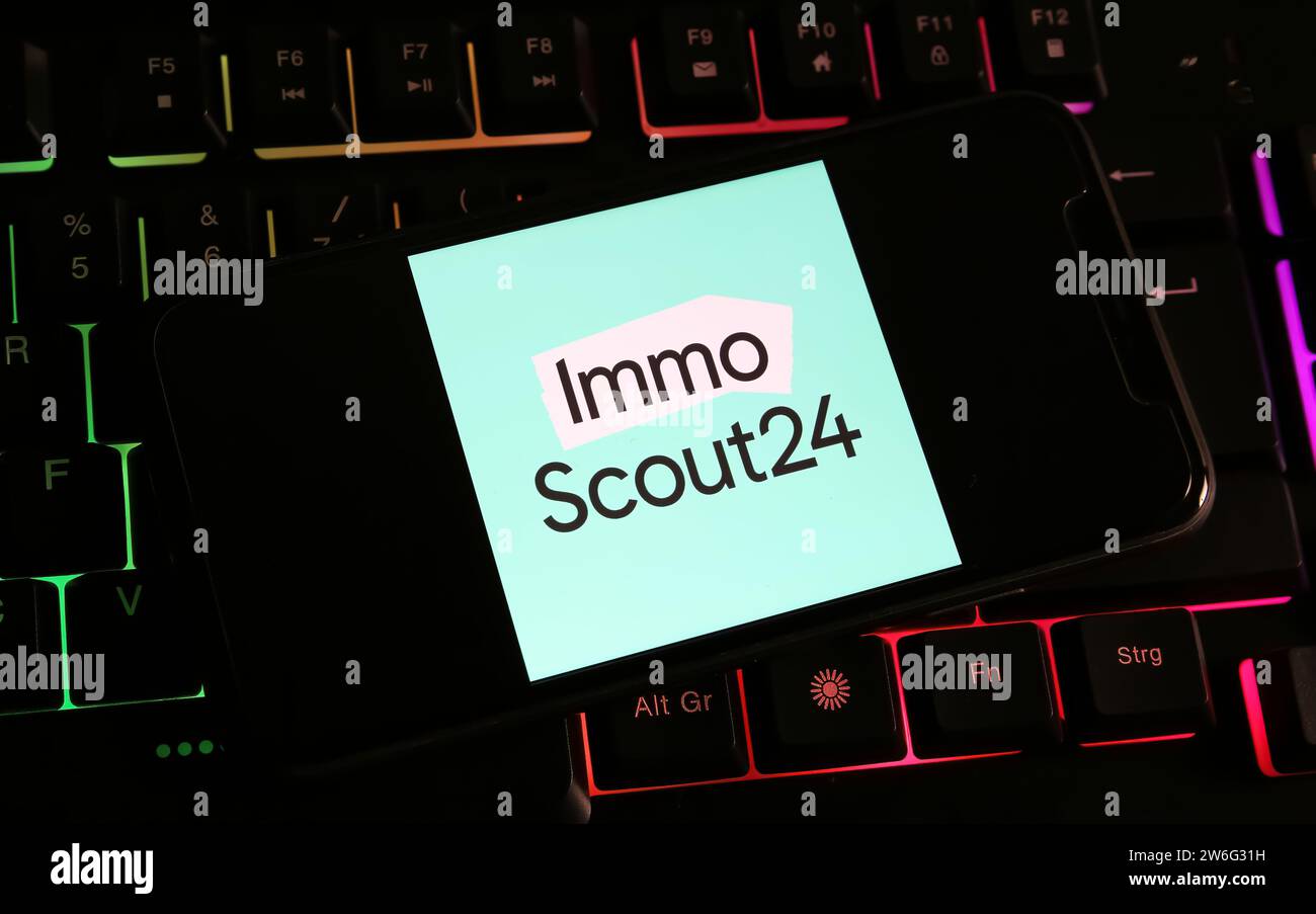 Viersen, Germania - 9 dicembre. 2023: Primo piano dello smartphone sulla tastiera del computer con il logo immo scout24 Foto Stock