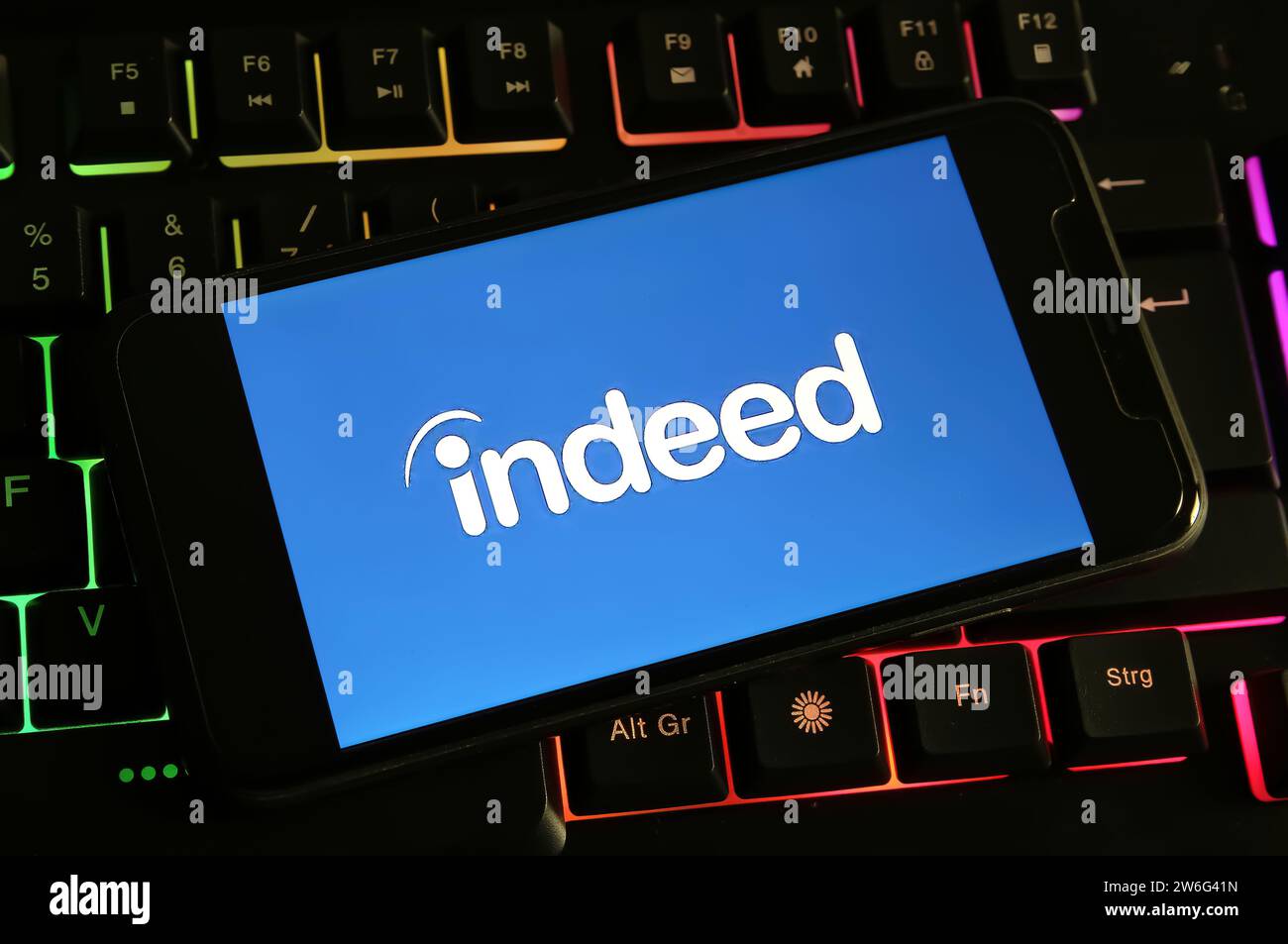 Viersen, Germania - 9 dicembre. 2023: Primo piano dello smartphone sulla tastiera del computer con il logo del portale di ricerca del lavoro Foto Stock