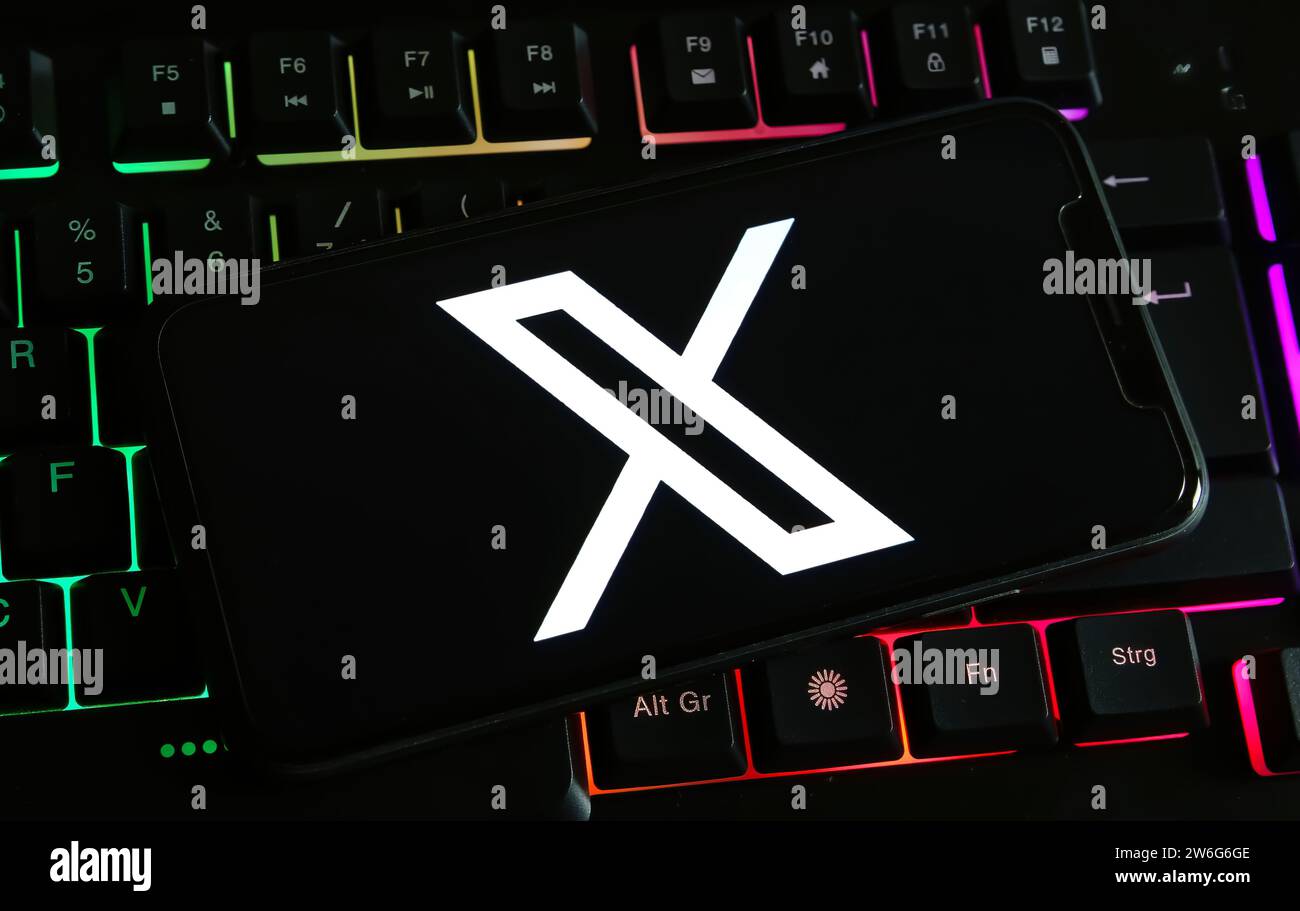 Viersen, Germania - 9 dicembre. 2023: Primo piano dello smartphone sulla tastiera del computer con il logo della X ex piattaforma di social media twitter Foto Stock