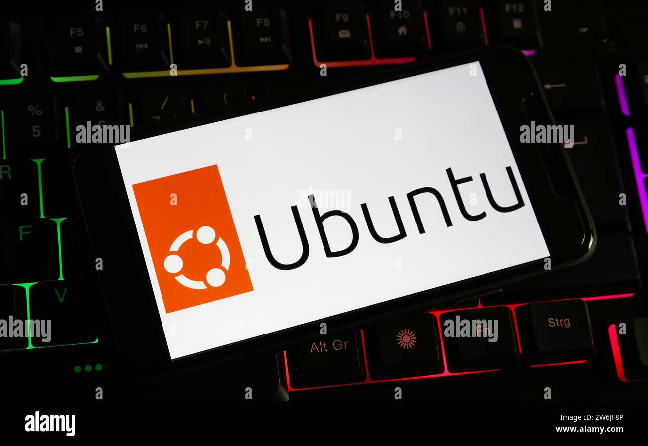 Viersen, Germania - 9 dicembre. 2023: Primo piano dello smartphone sulla tastiera del computer con il logo di Ubuntu Foto Stock