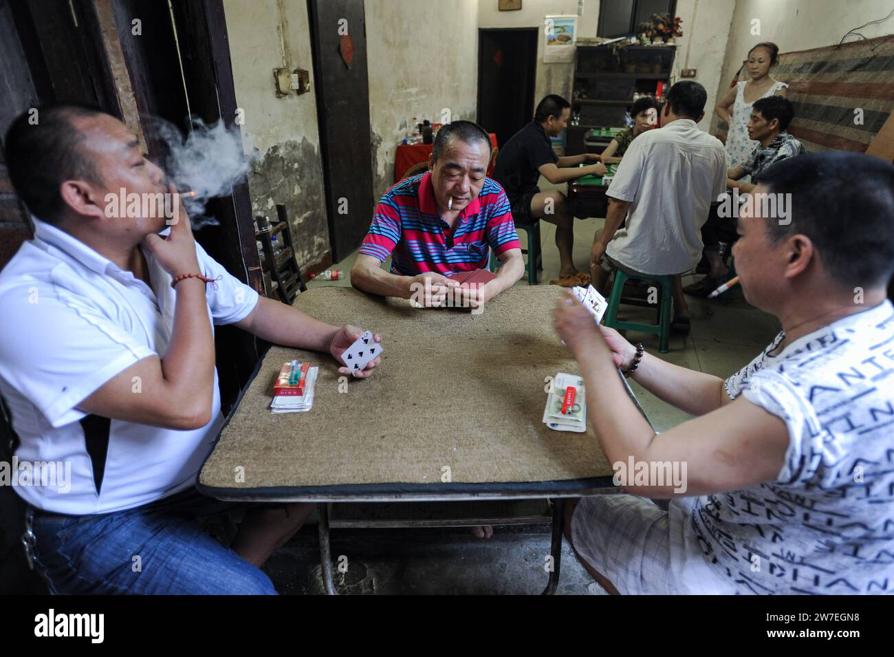 04.08.2012, Cina, Chongqing, - gli uomini cinesi fumano sigarette seduti ad un tavolo e giocano a carte nell'area di diciotto scale della citta' vecchia Foto Stock