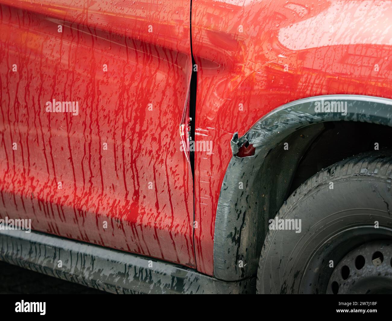 Danni alla carrozzeria dopo una collisione nel parcheggio. Graffi e lamiere deformate all'esterno. Il problema è dietro la ruota anteriore. Foto Stock