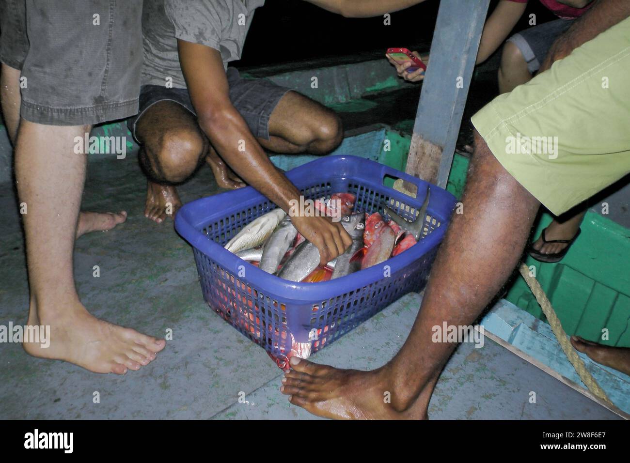 Maldive - 5 ottobre 2013: Un gruppo di pescatori in un'amichevole pesca notturna con un cestino pieno di pesce. Foto Stock