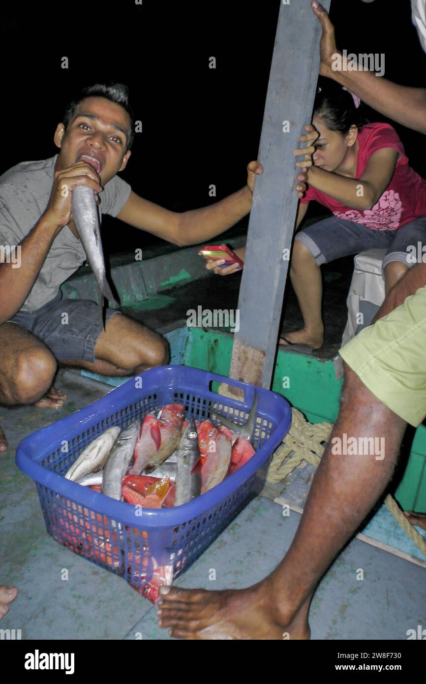 Maldive - 5 ottobre 2013: Un gruppo di pescatori in un'amichevole pesca notturna con un cestino pieno di pesce. Foto Stock