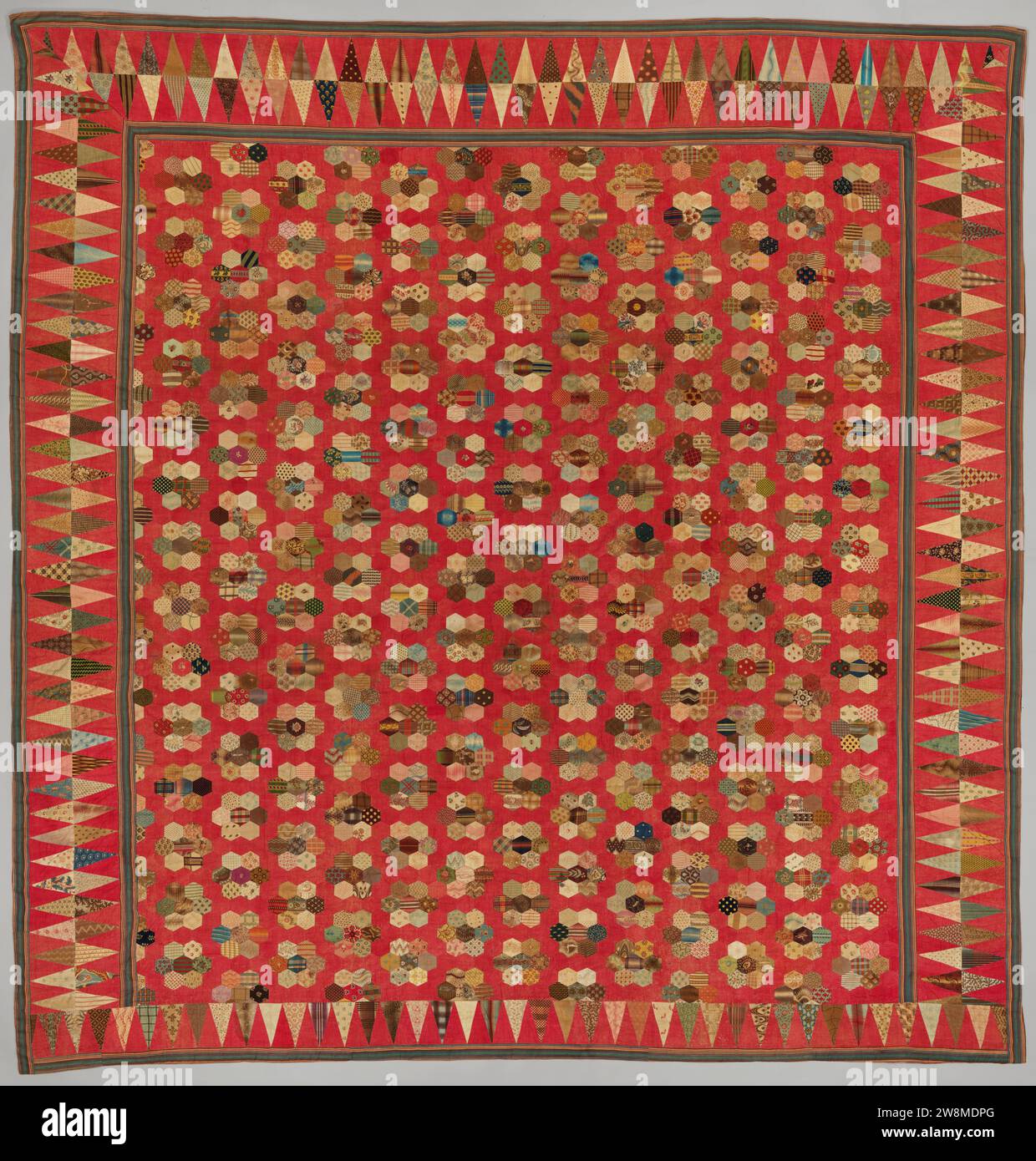 Copriletto in patchwork di cotone stampato con motivo di rose , 1800 - 1850 copriletto in patchwork di cotone stampato. Le rose collocate al centro di corsie che formano file sfalsate orizzontalmente si trovano contro un brodo rosso, anch'esso di esagoni. Ciascuna delle rose è composta da sette esagoni, combinati in modo casuale. Il bordo è simile a un piatto Tric trac con triangoli allungati di cotone di pelliccia, cuciti insieme, che risaltano contro i triangoli pieni in rosso. Elenchi interni ed esterni a righe verdi. Copriletto per stampa in cotone (tessile) olandese in patchwork di cotone stampato. Rose collocate in mezzo a corsie per Foto Stock