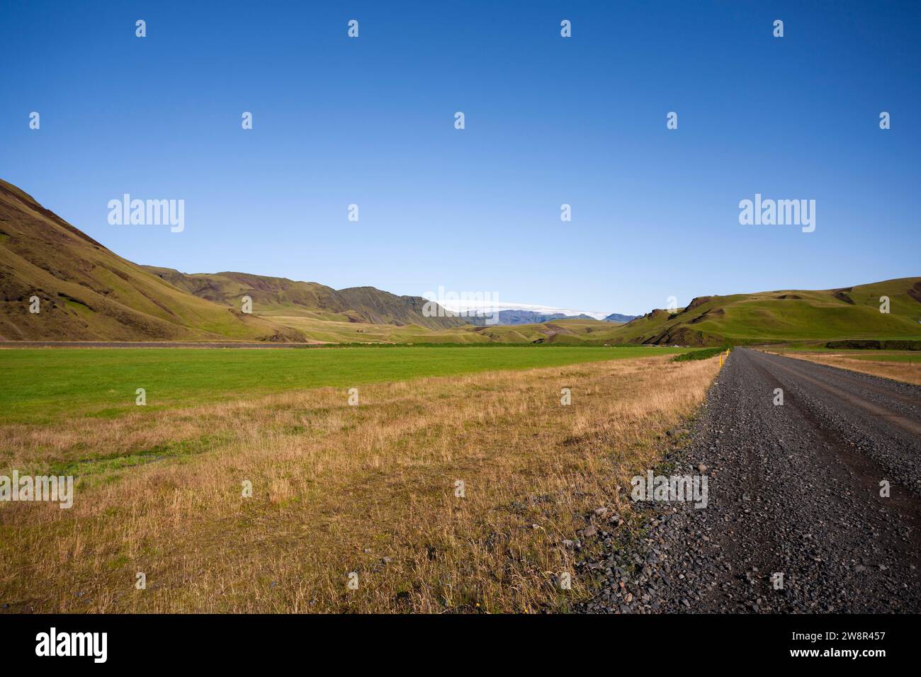 Strada di ghiaia nera attraverso il panoramico paesaggio montano, l'Islanda Foto Stock
