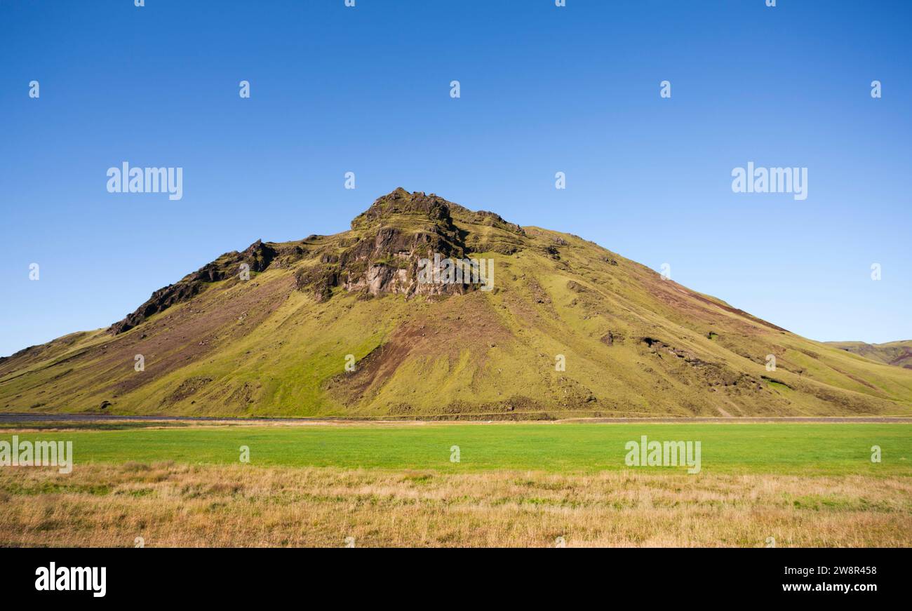 Montagna con pendii ricoperti di erba verde in un paesaggio panoramico, Islanda Foto Stock