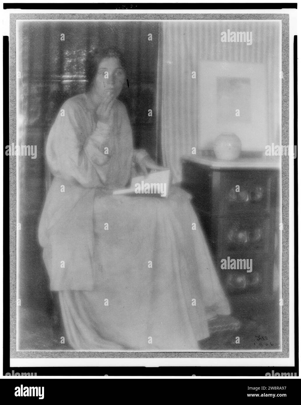 Donna (Beatrice Baxter Ruyl), nel vestire con il libro aperto in giro e mano per affrontare, seduto Foto Stock