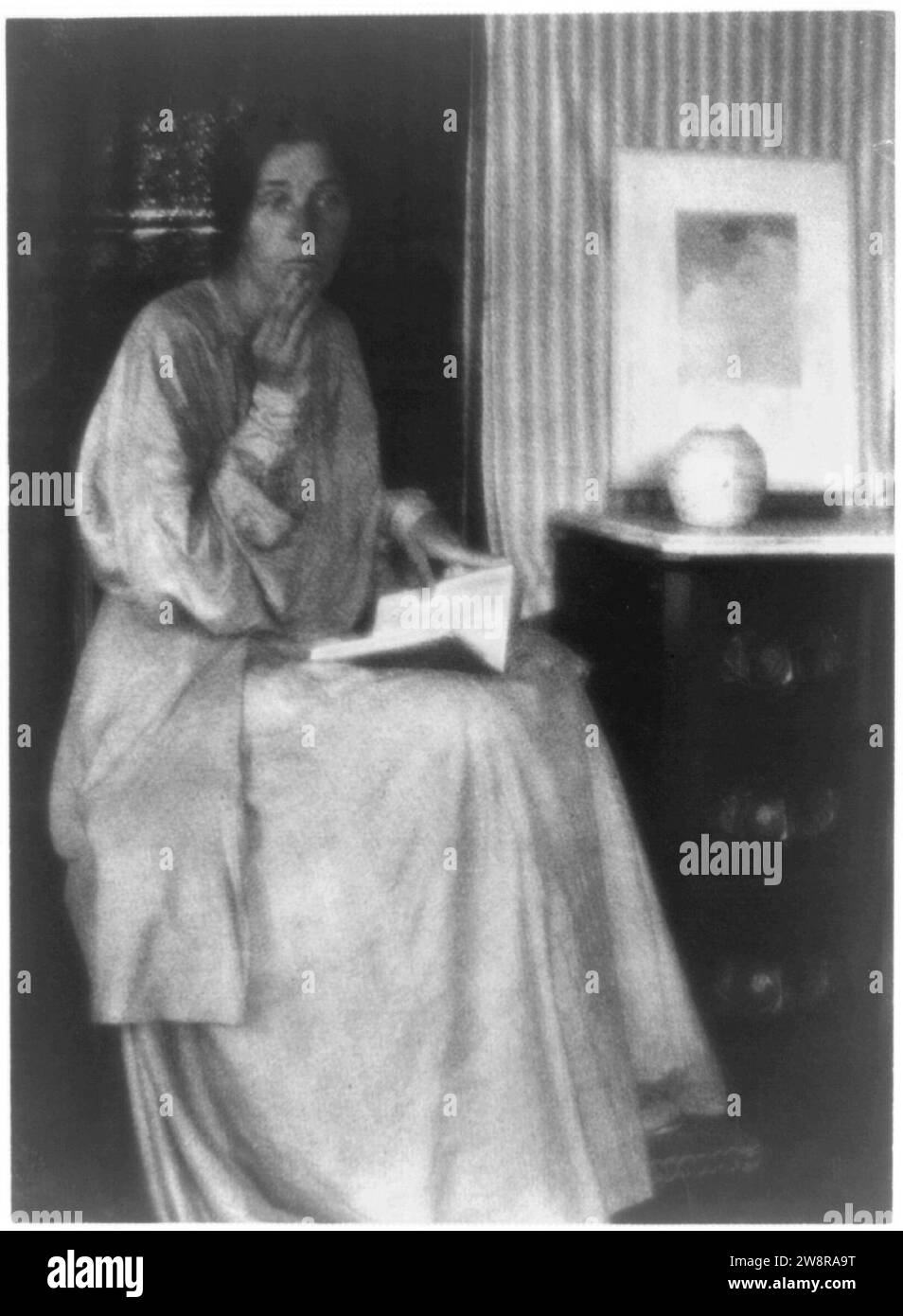 Donna (Beatrice Baxter Ruyl), nel vestire con il libro aperto in giro e le mani alla faccia, seduto Foto Stock