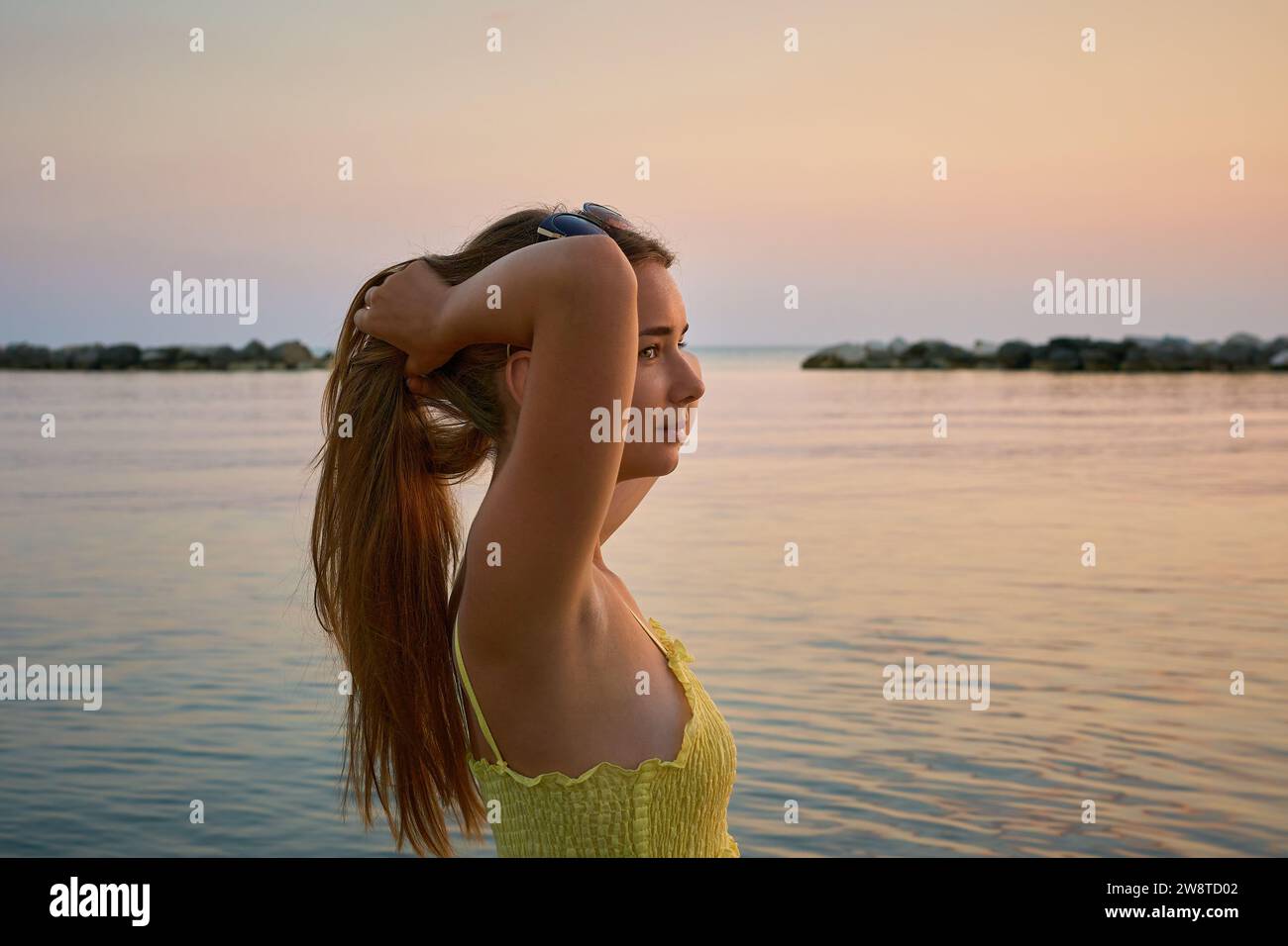 Giovane viaggiatrice che si posa sulla spiaggia in riva al mare all'alba e condivide il suo viaggio avventuroso. Foto Stock