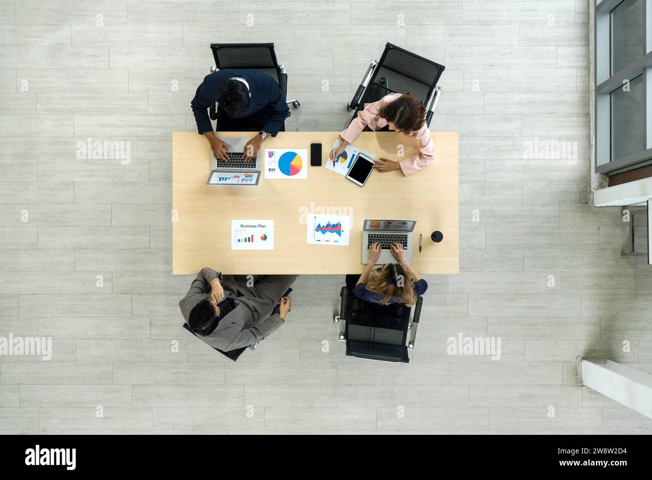 Un team di lavoratori è seduto insieme a un grande tavolo in un ufficio, condividendo pensieri e parlando. Vista dall'alto Foto Stock