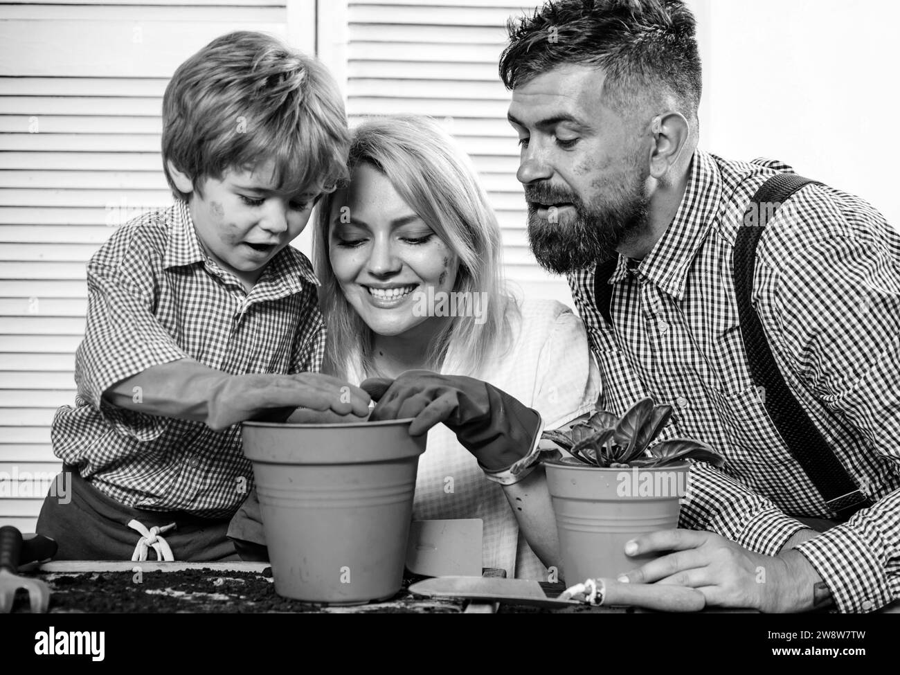 Giovani genitori felici mamma papà con bambino, famiglia giorno paternità concetto di infanzia. Allegro tre persone con cute bambino che cresce pianta in vaso. Foto Stock