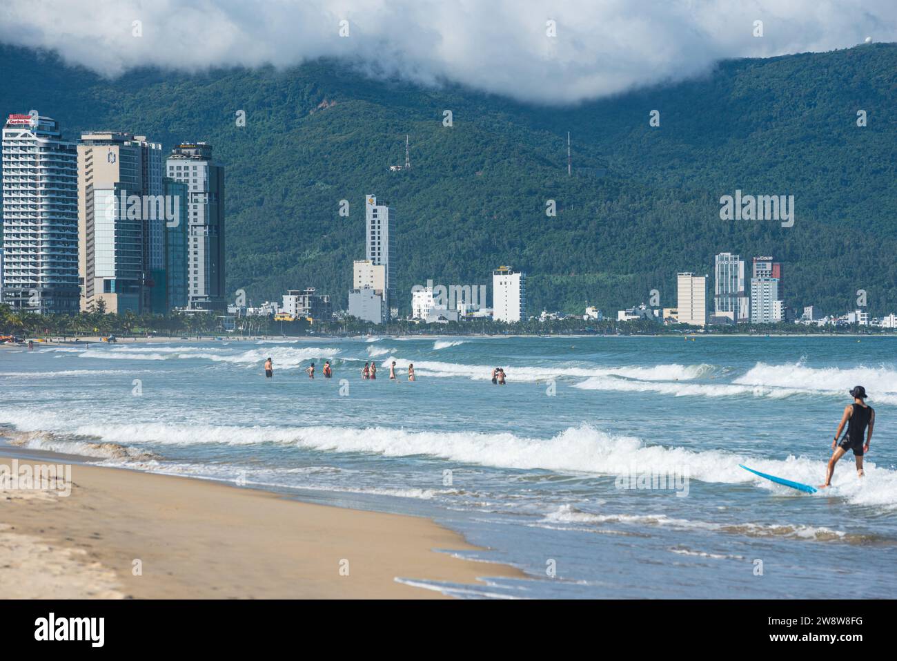 Da Nang, Vietnam - 4 ottobre 2023: spiaggia con nuotatori e una serie di hotel moderni in lontananza. Foto Stock