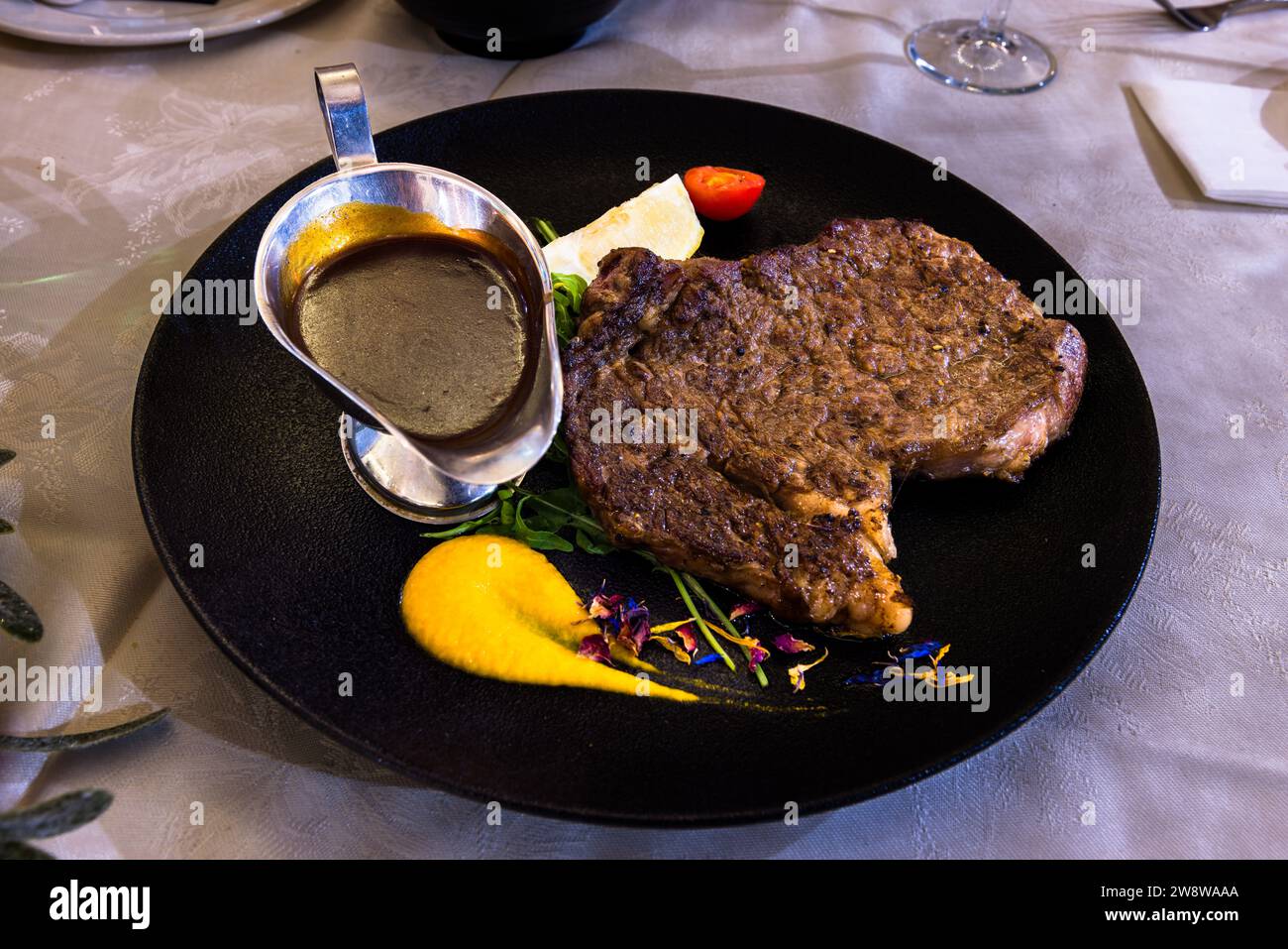Un abbondante bistecca grigliata con un jus scuro, purè giallo e fiori commestibili viene servita al ristorante "Country Terrace" a Għajnsielem sull'isola di Gozo, Malta. Foto Stock