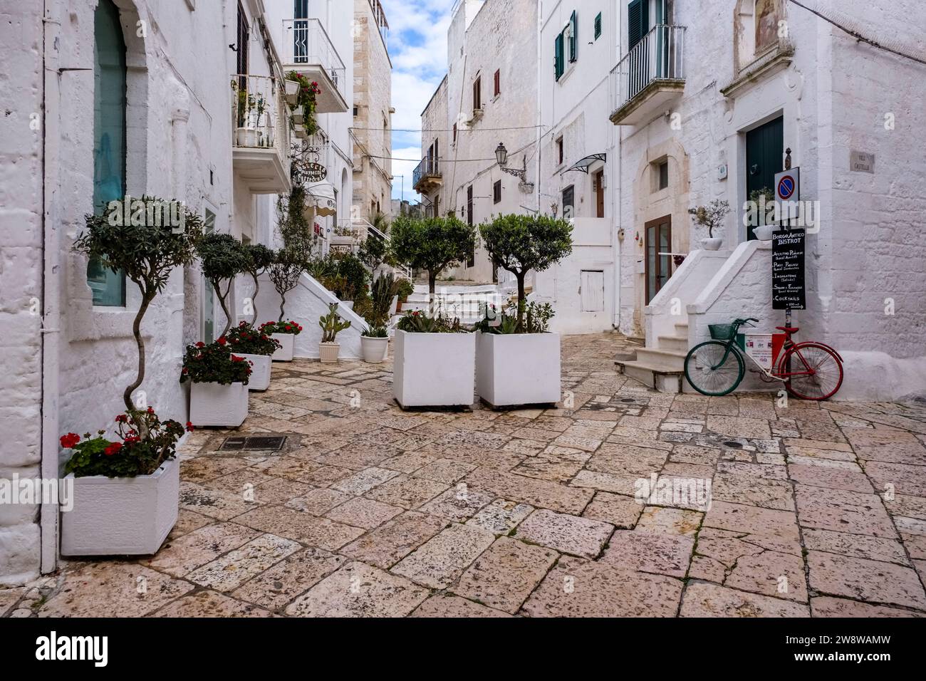 Scena di strada con una piccola piazza tra case, balconi, scalinate e piante verdi in vaso. Foto Stock