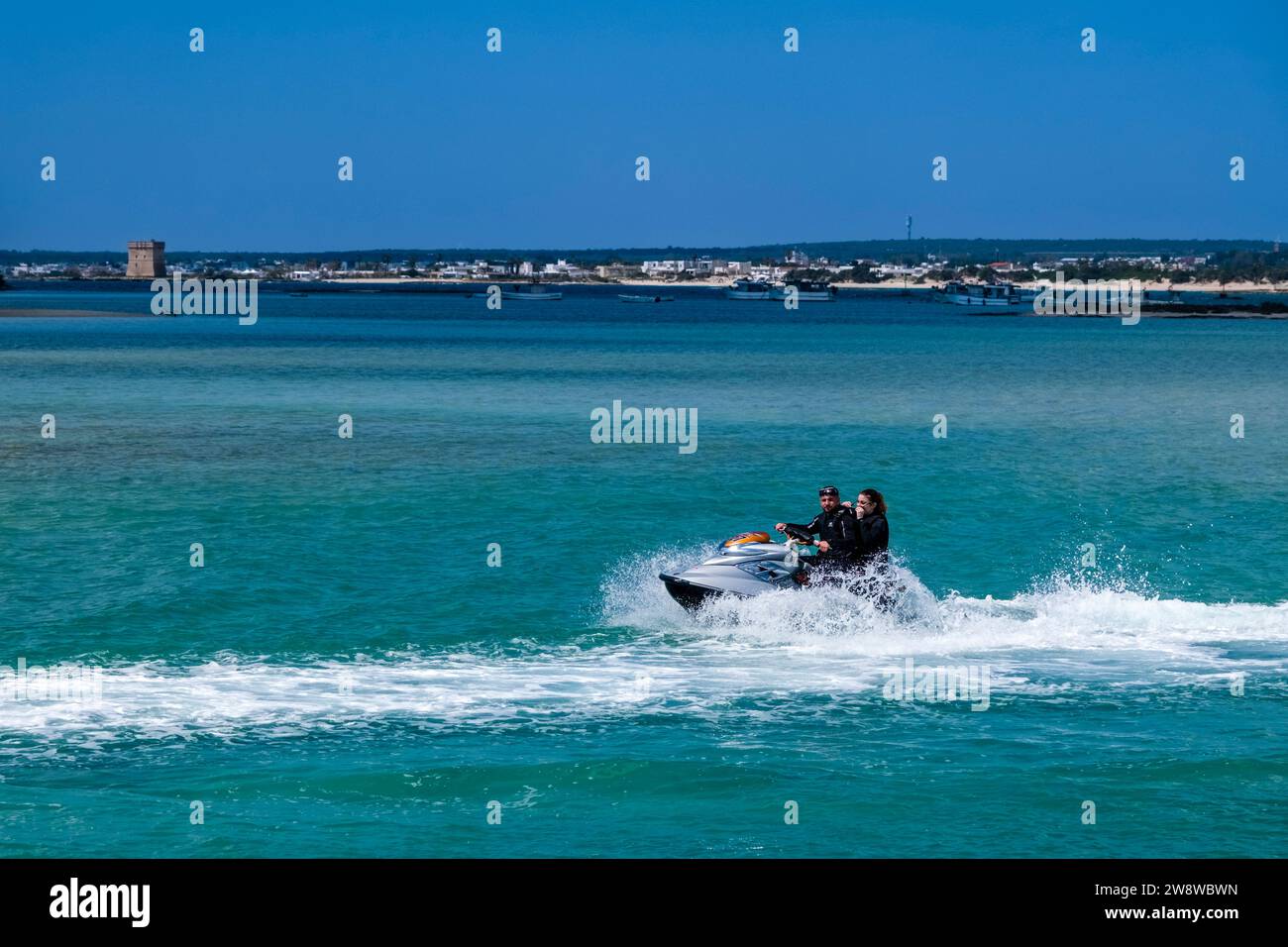 Una moto d'acqua con due persone che navigano nella baia poco profonda. Foto Stock