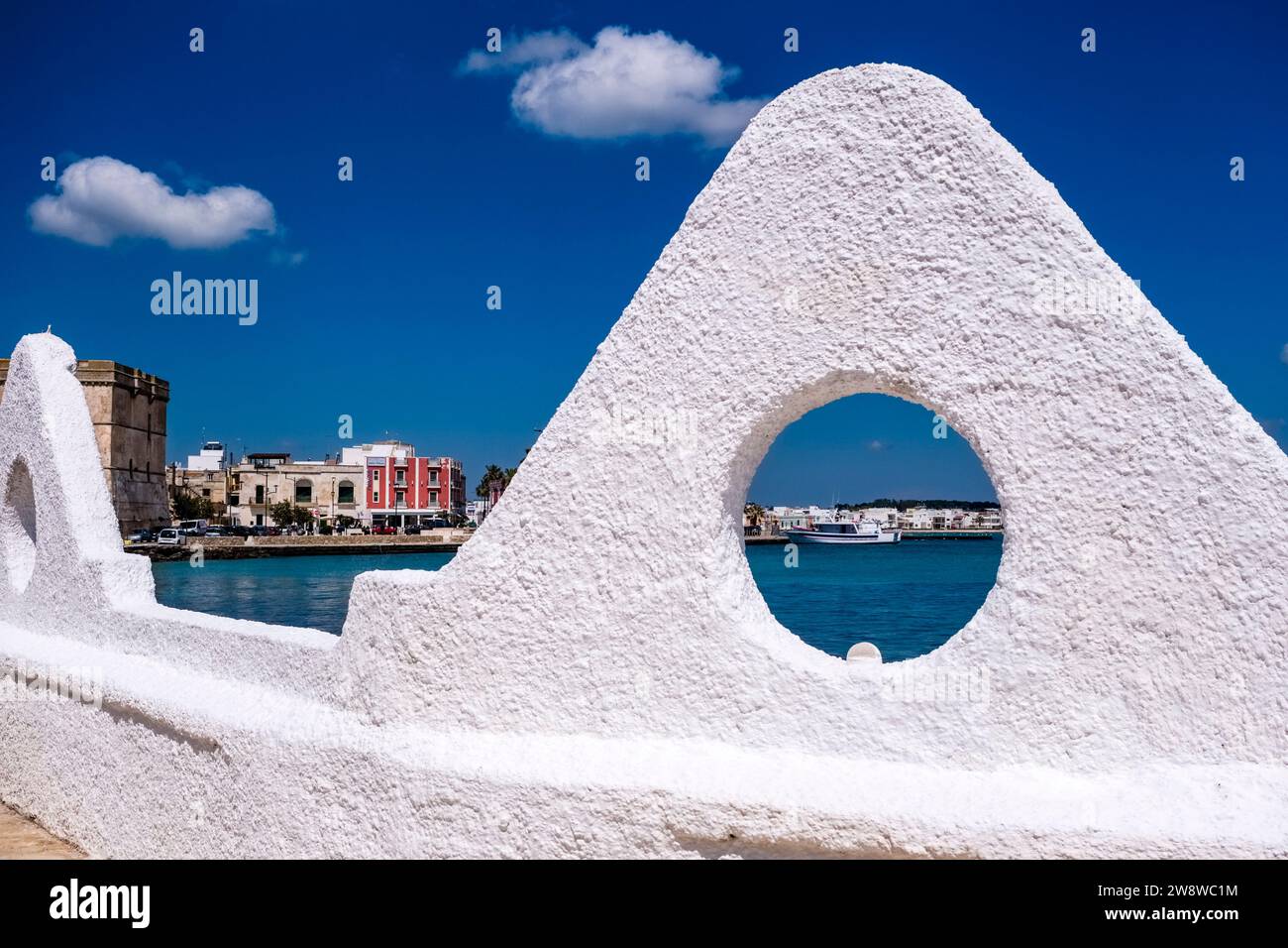Case sulla riva della piccola città, un peschereccio all'ancora nella baia poco profonda, visto da una finestra su un muro bianco. Foto Stock