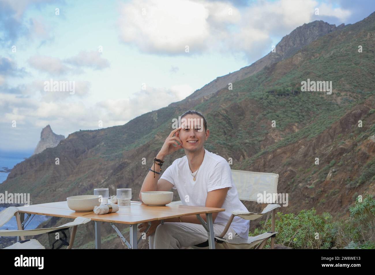 Un sereno momento di solitudine, un individuo che si gusta un pasto in mezzo alla bellezza della natura sotto un cielo luminoso Foto Stock