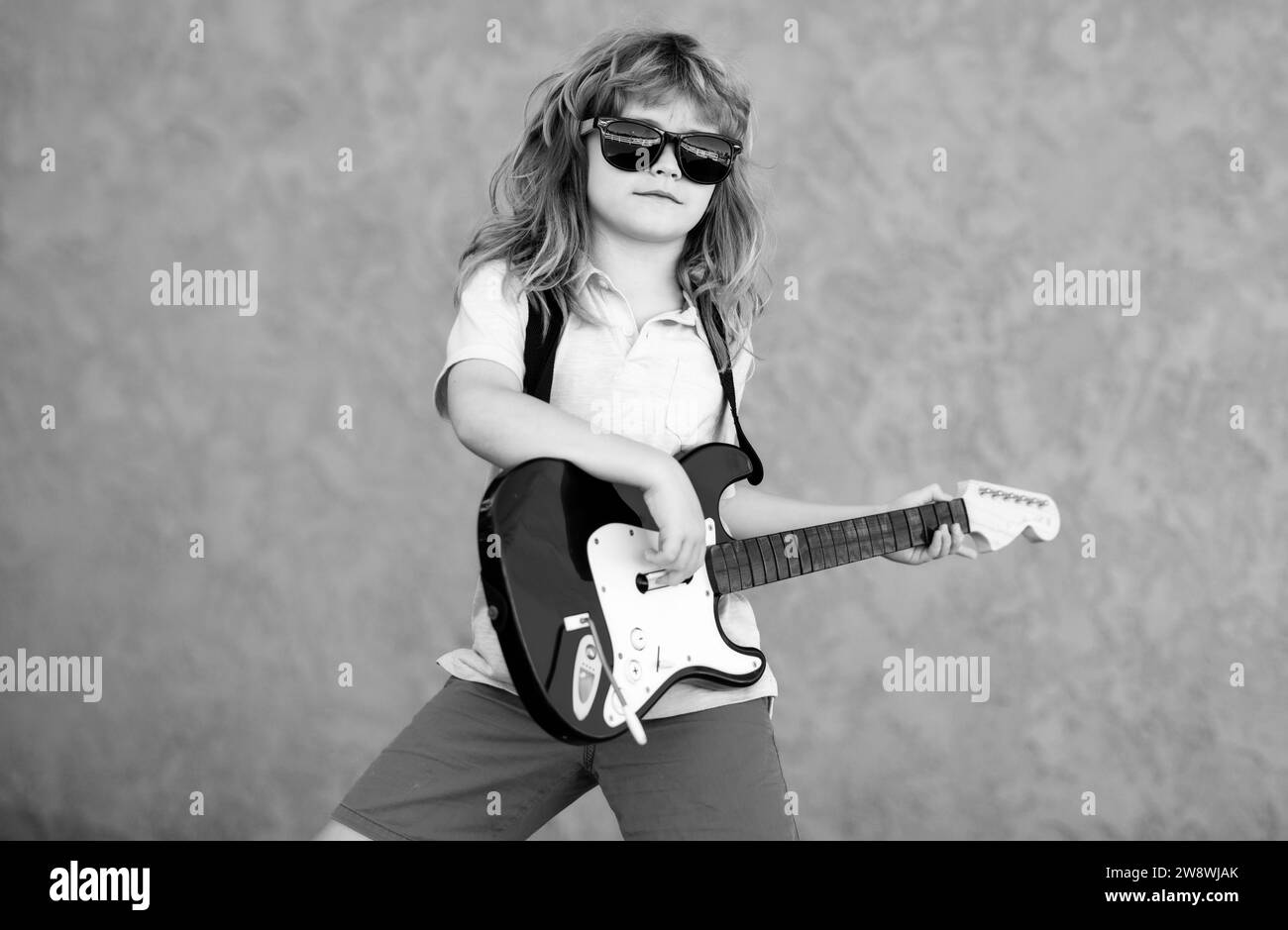 Ragazzo con chitarra. Il bambino suona una chitarra e canta, musica e canzone per bambini. Chitarrista musicista bambino che suona la chitarra elettrica. Foto Stock