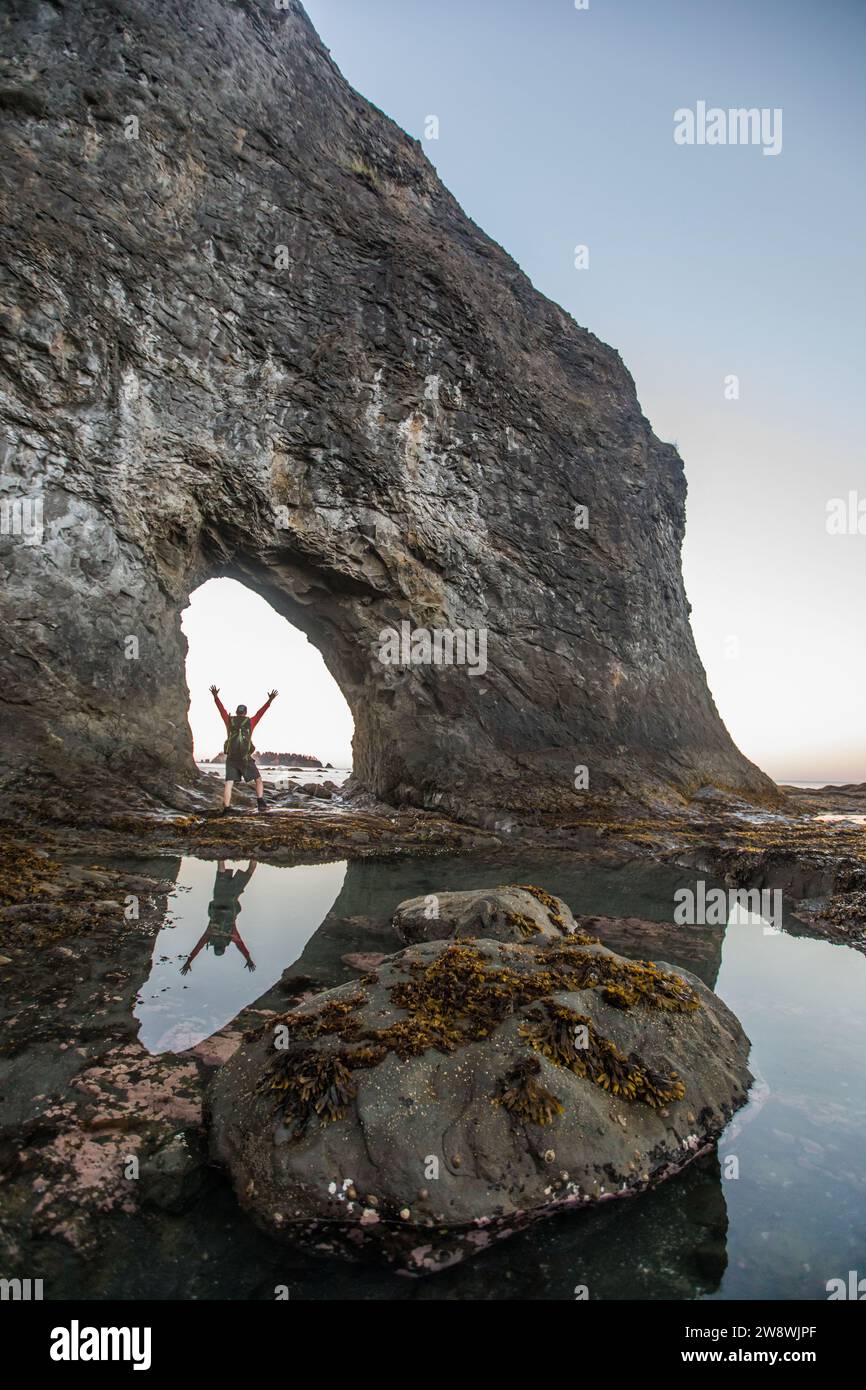 Reflection of Backpacker con bracci sollevati in corrispondenza di Hole-in-the-Wall Foto Stock