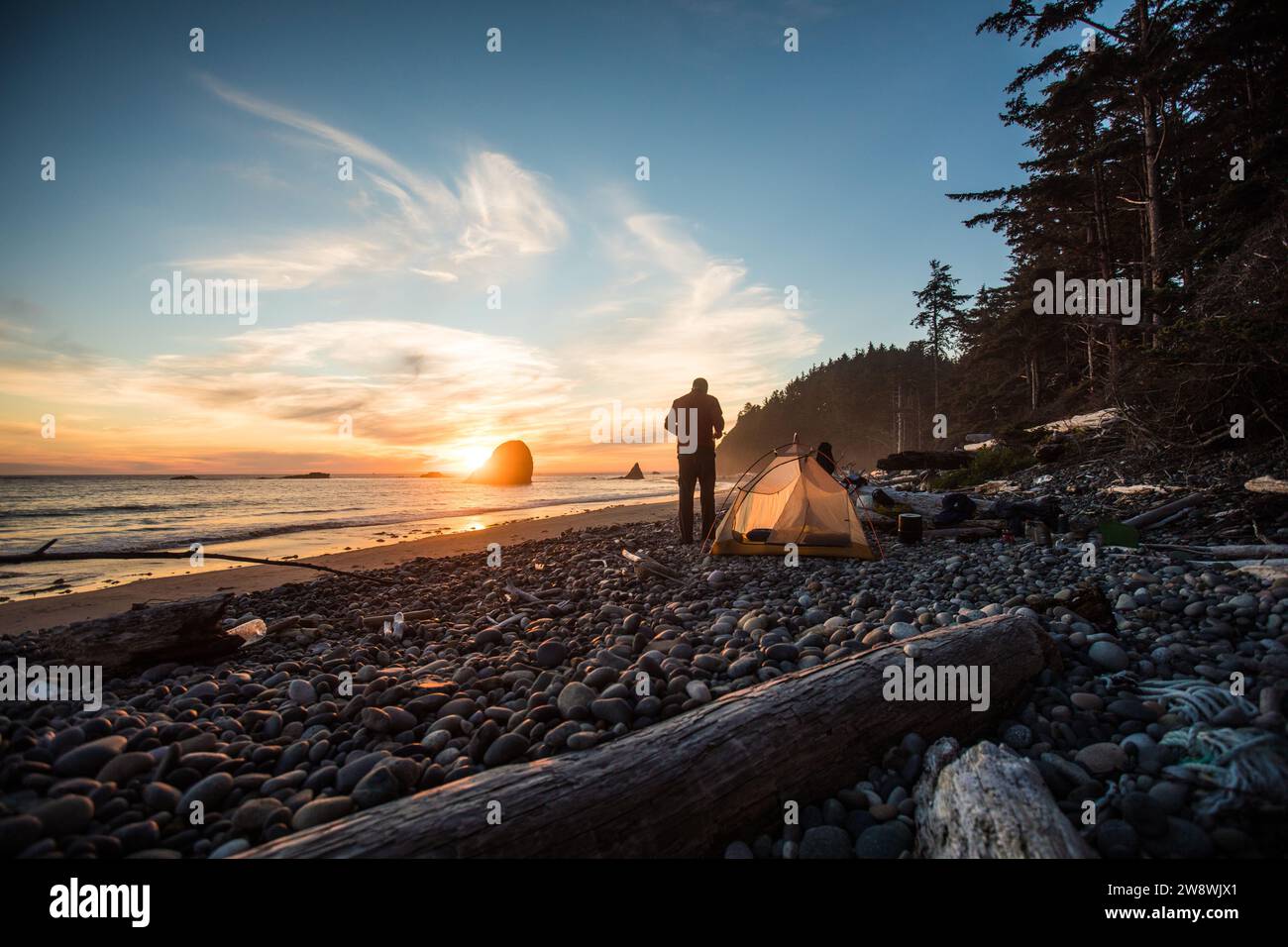 Uomo e tenda disposti sulla spiaggia al tramonto, all'Olympic National Park Foto Stock