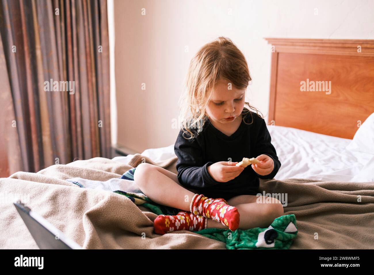 Una ragazza seduta su un letto in una camera da letto Foto Stock