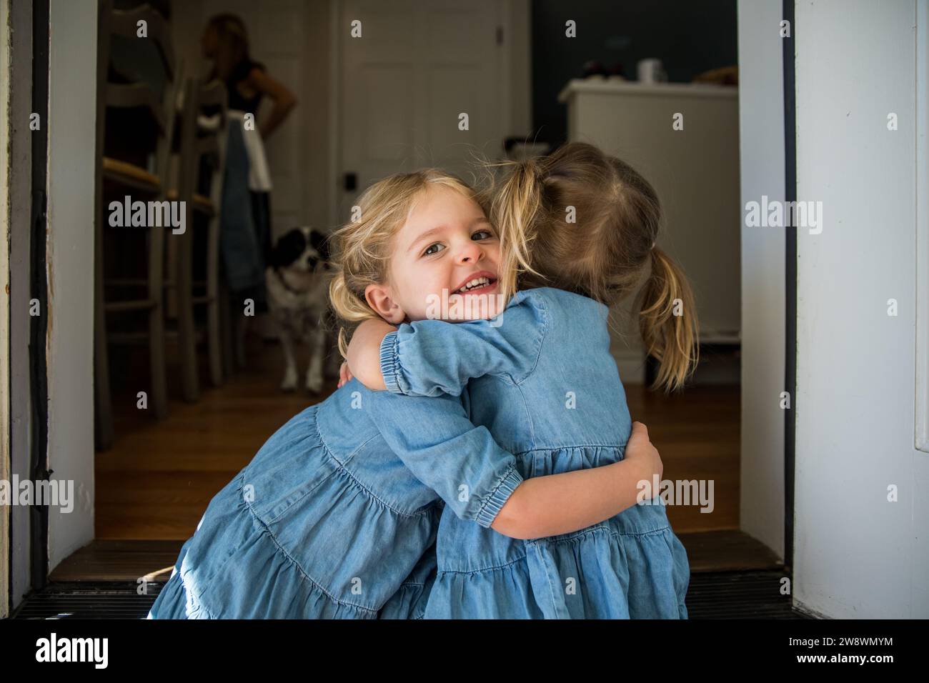 Giovani sorelle che si abbinano e si abbracciano alla porta Foto Stock