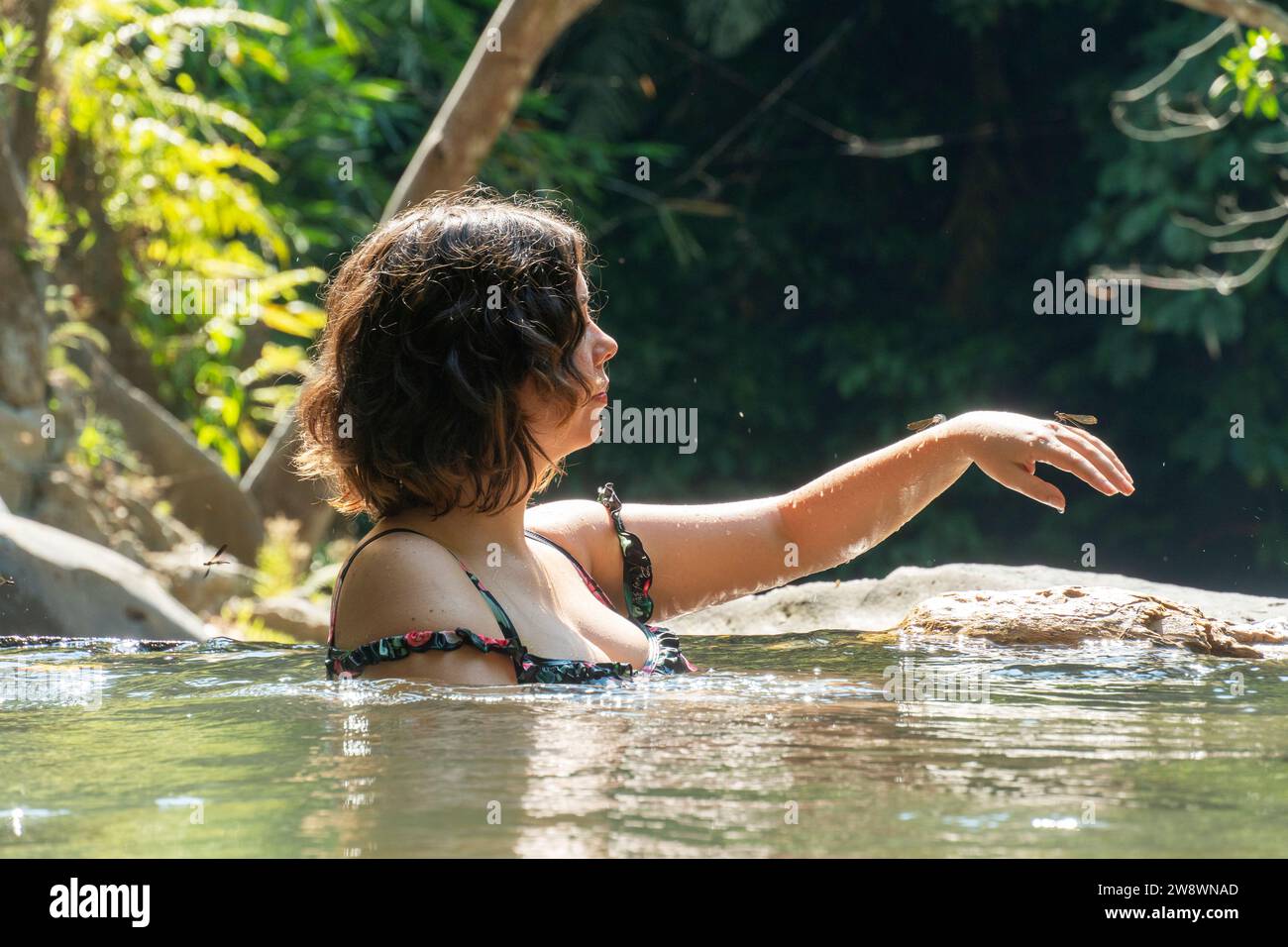 Giovane donna in acqua con la libellula a portata di mano. Foto Stock