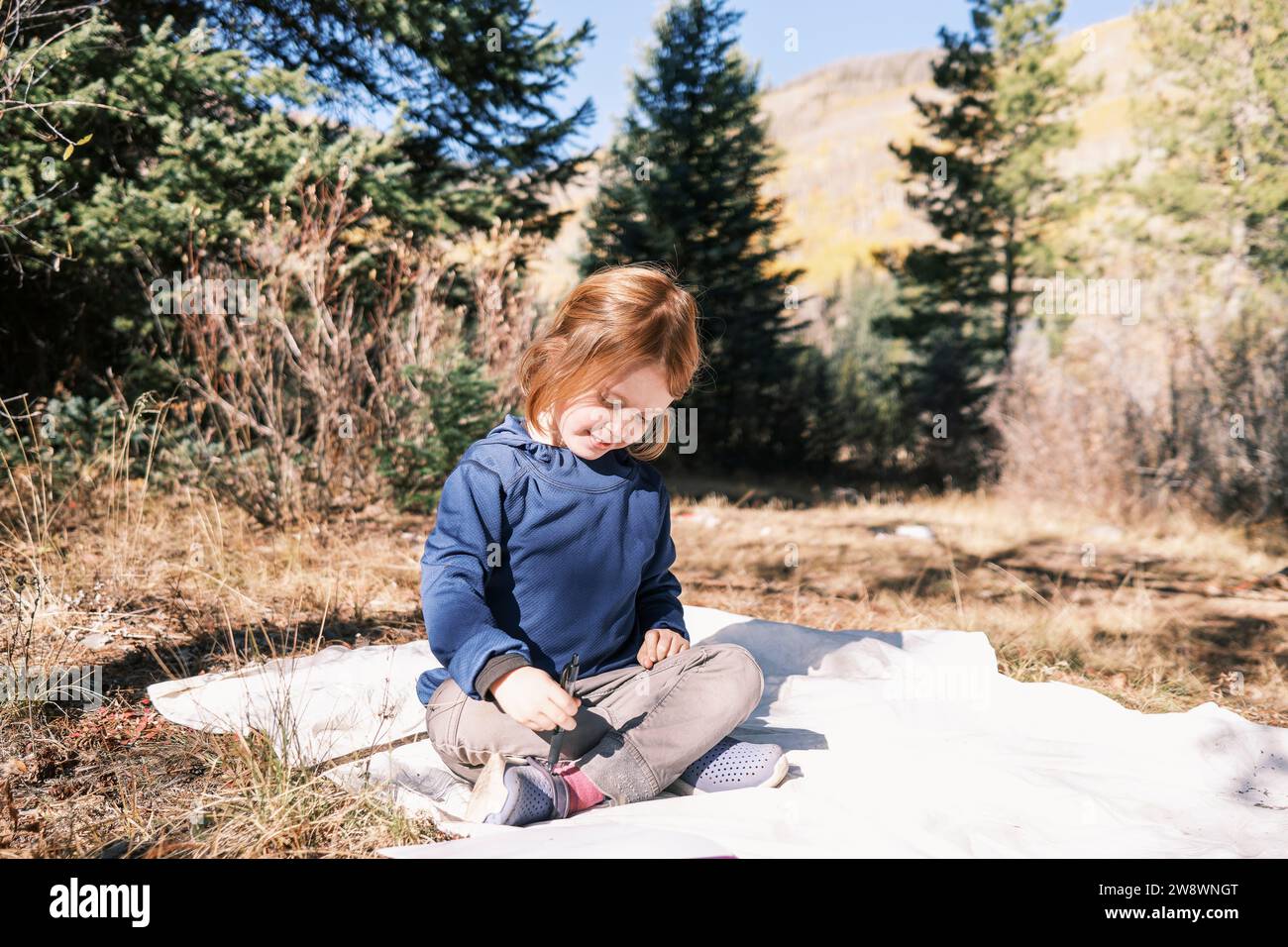 Bambino sorridente seduto al sole durante un viaggio in campeggio Foto Stock
