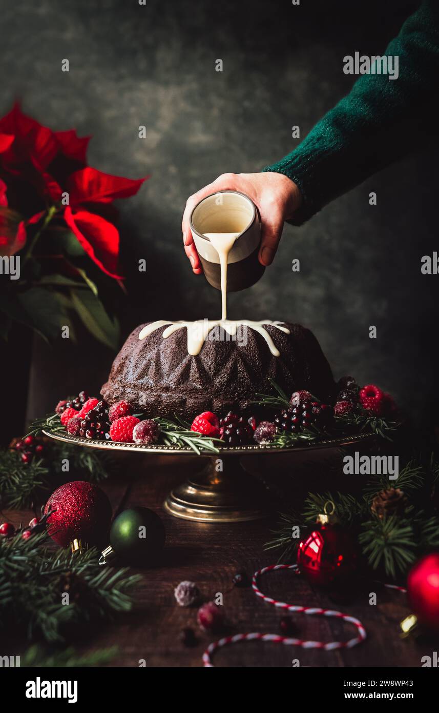 Versare a mano la glassa sulla torta natalizia. Foto Stock